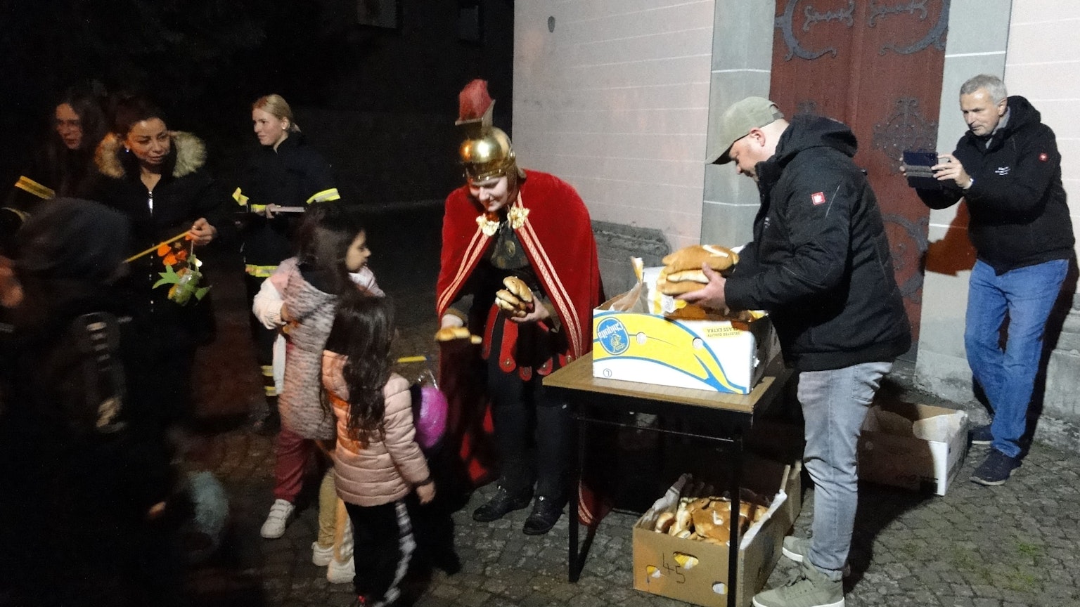 Eine Frau im Martinskostüm verteilte vor der Kirche St. Amandus in Rheinkassel nach dem Zug Weckmänner an die Kinder.