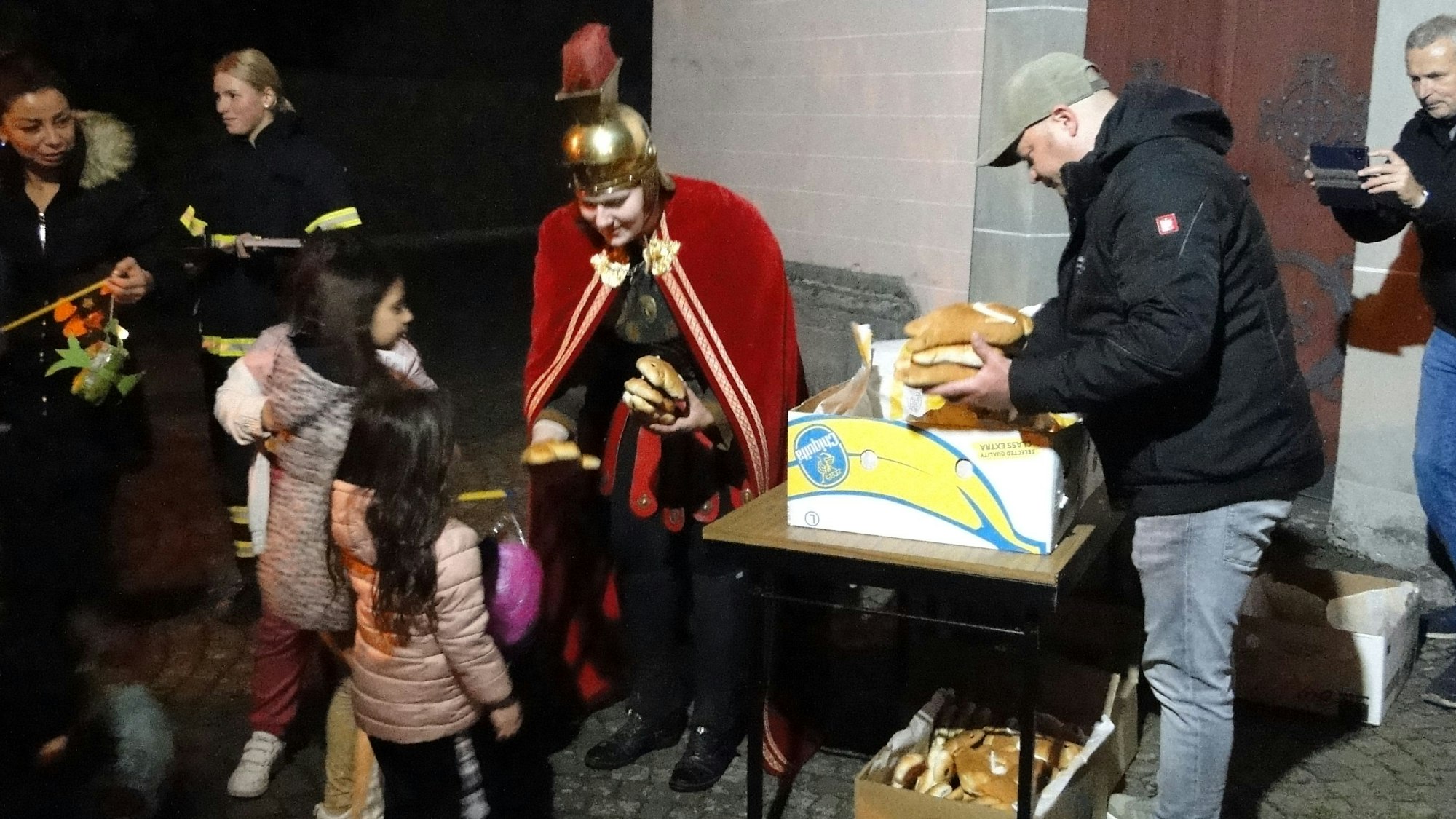 Eine Frau im Martinskostüm verteilte vor der Kirche St. Amandus in Rheinkassel nach dem Zug Weckmänner an die Kinder.