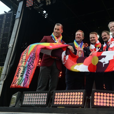 Der neue Mottoschal wird von mehreren Karnevalisten hochgehalten.