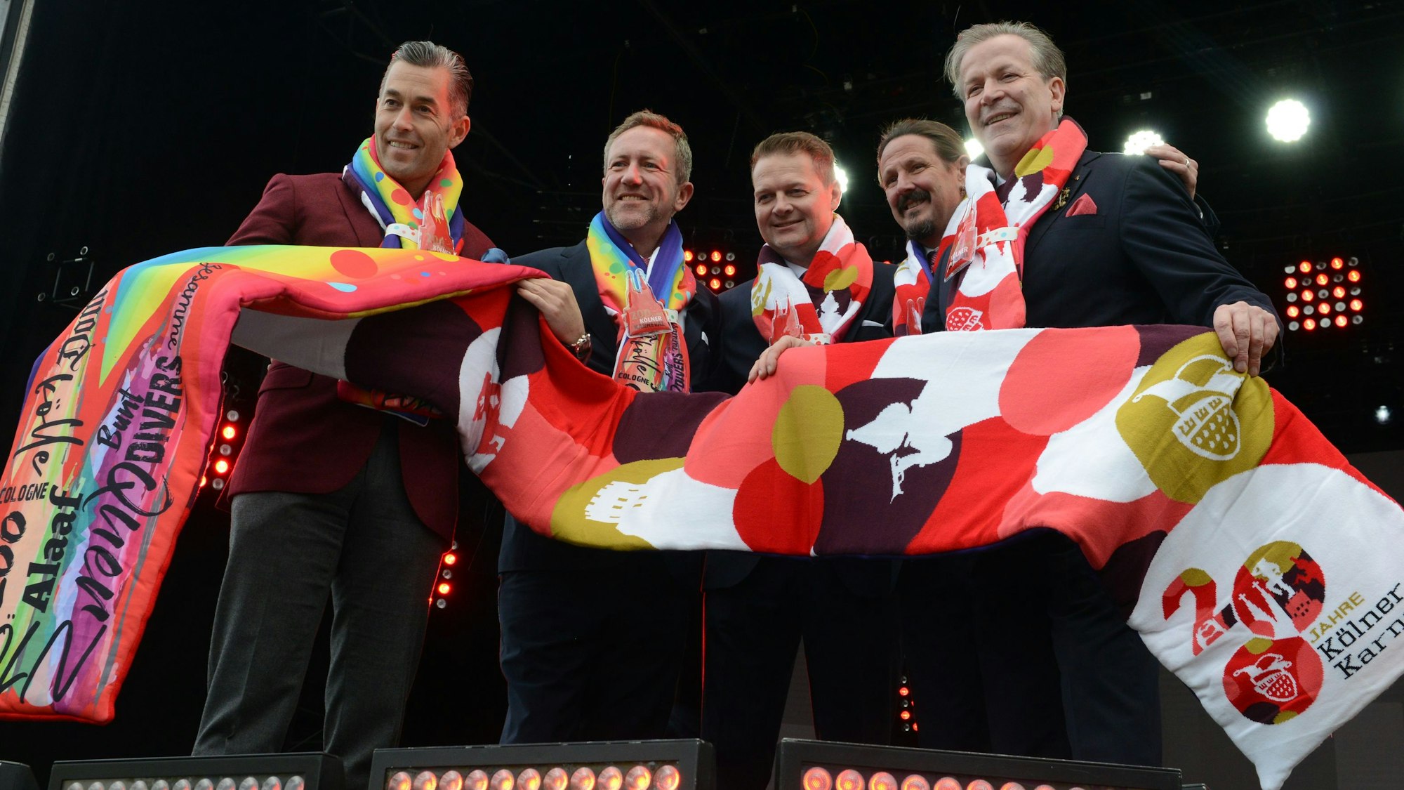 Der neue Mottoschal wird von mehreren Karnevalisten hochgehalten.