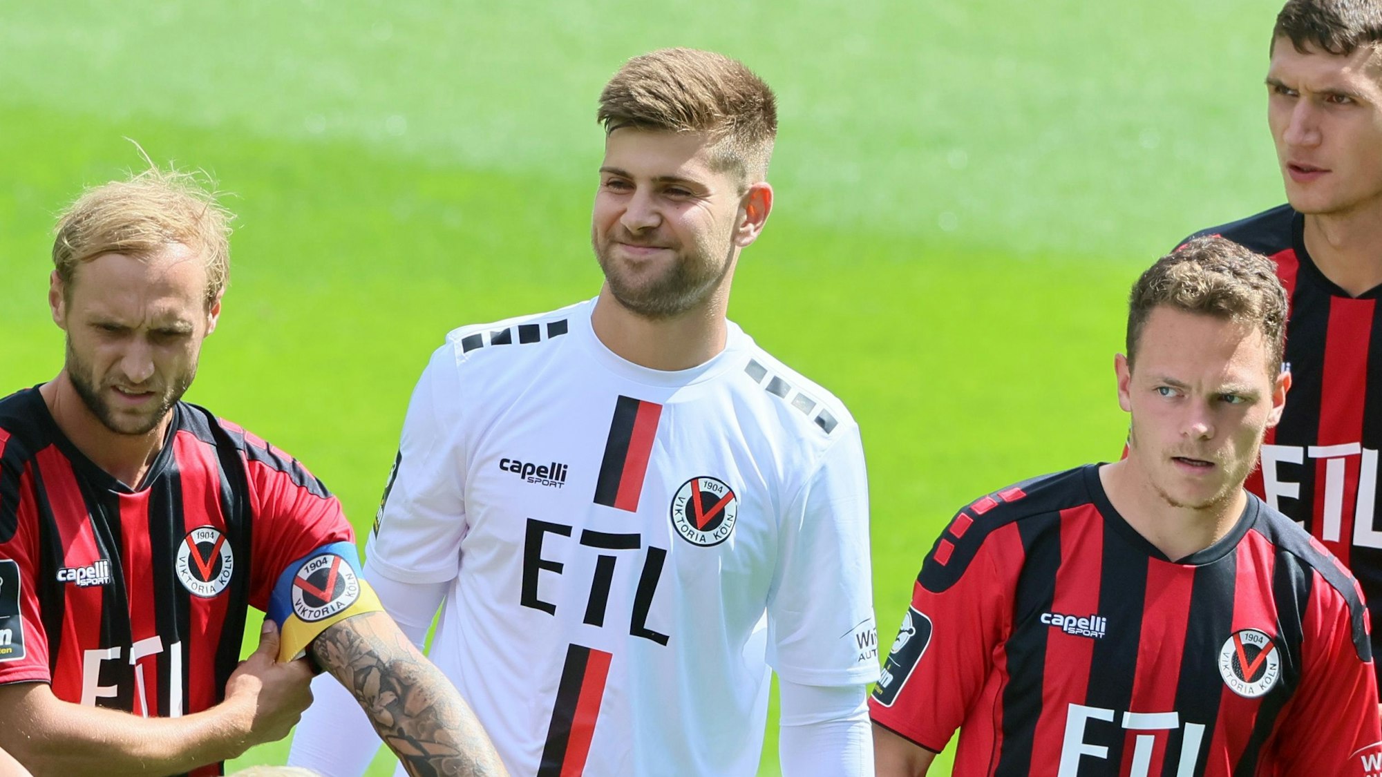 Vier Fußballspieler bei der Team-Präsentation, in der Mitte ein lächelnder Torhüter