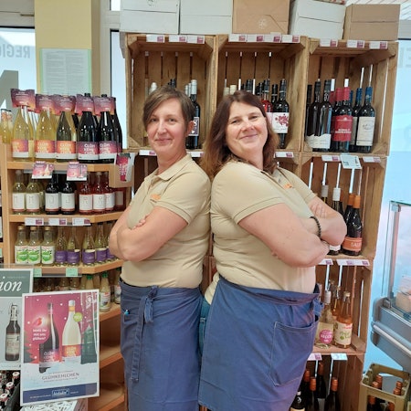 Saskia und Ulrike Effey stehen vor einem Regal voller Bio-Weine und Säfte.