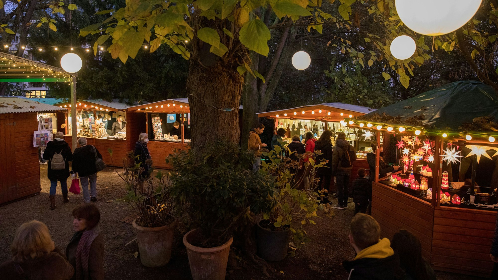 Menschen stehen vor den Hütten auf dem Weihnachtsmarkt im Stadtgarten.