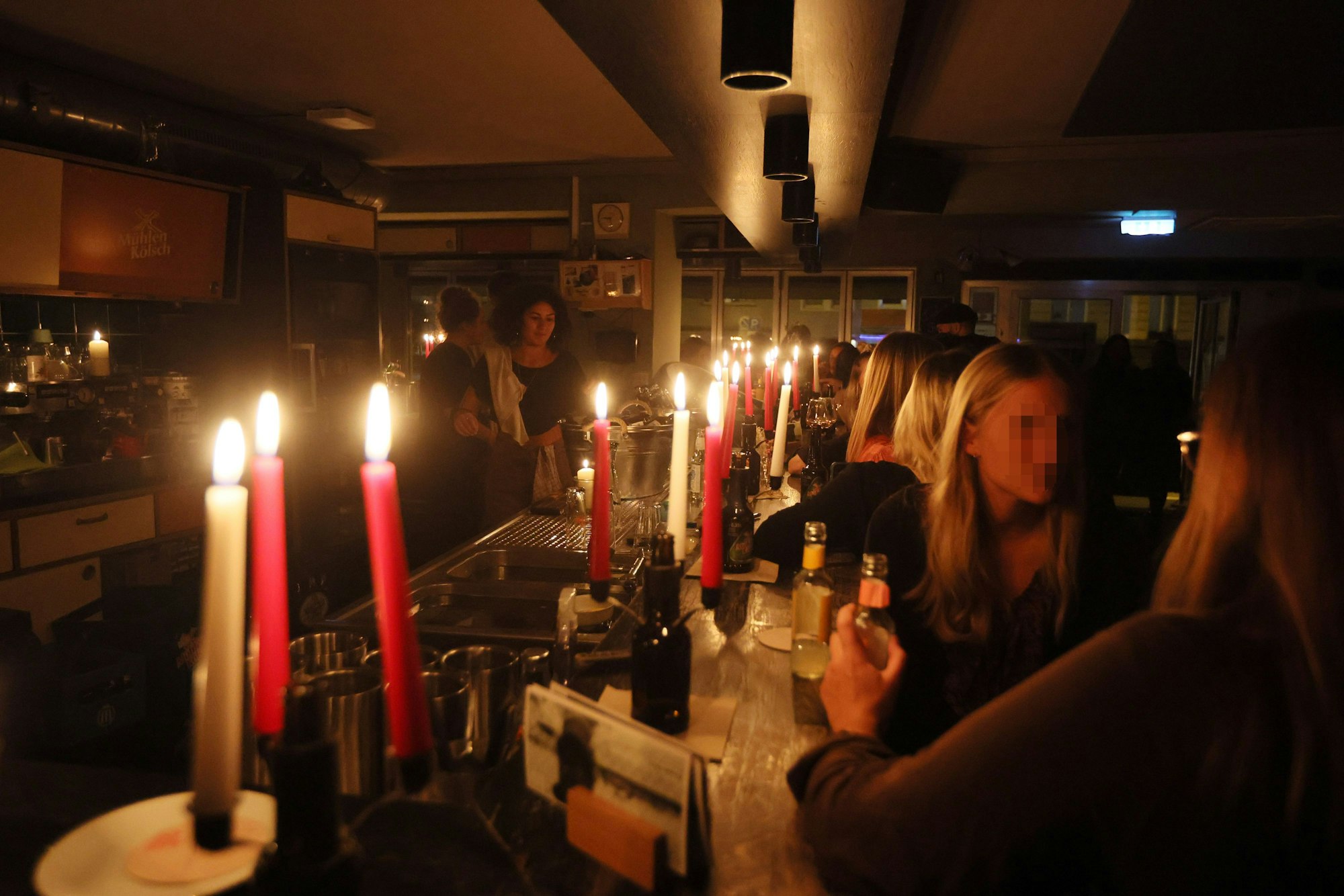 Besucher sitzen bei Kerzenschein am Tresen in der Bar Wohngemeinschaft.