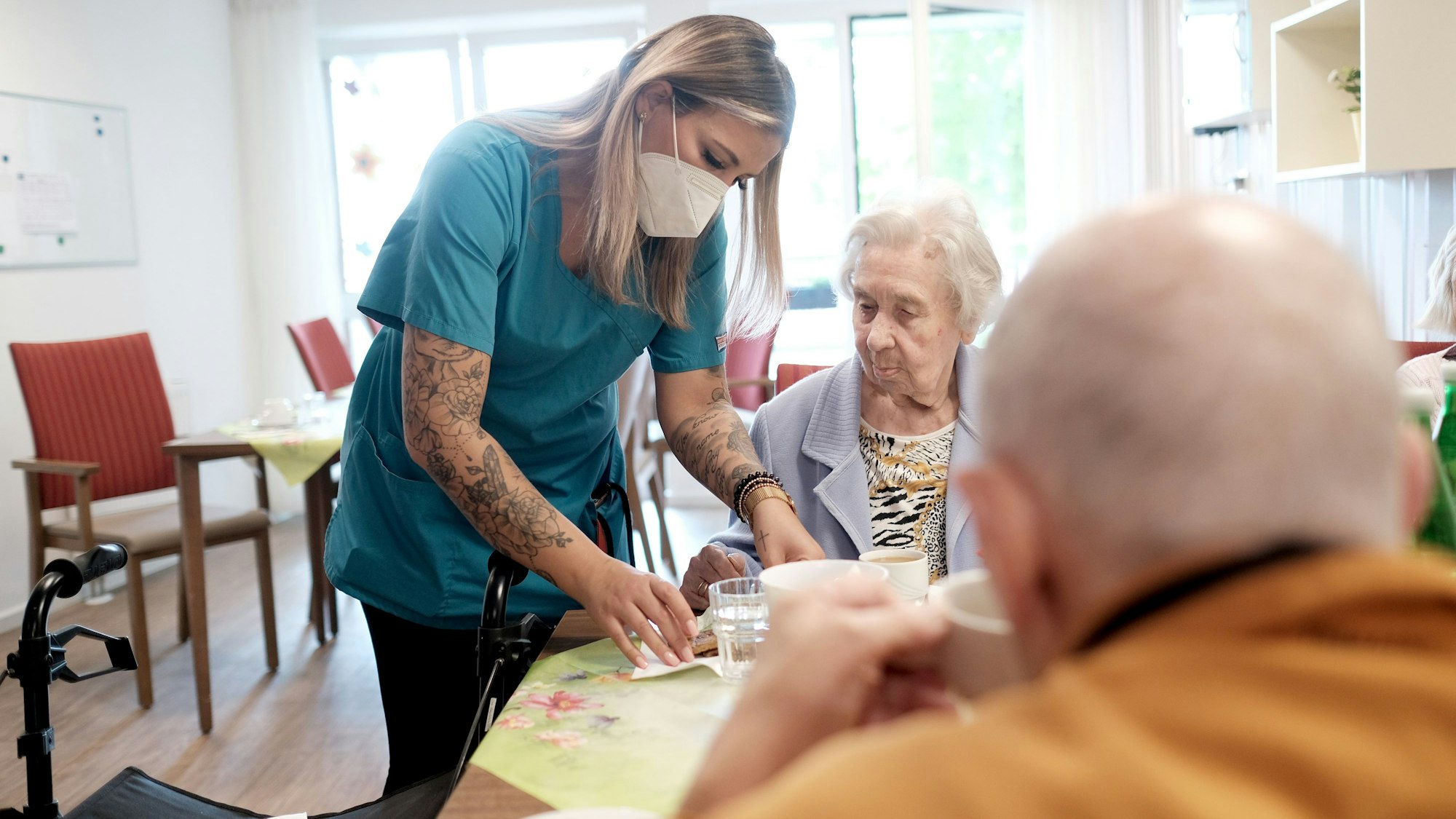 Im Caritas-Zentrum St. Maternus in Rodenkirchen kümmert sich eine Pflegerin um zwei Heimbewohner.