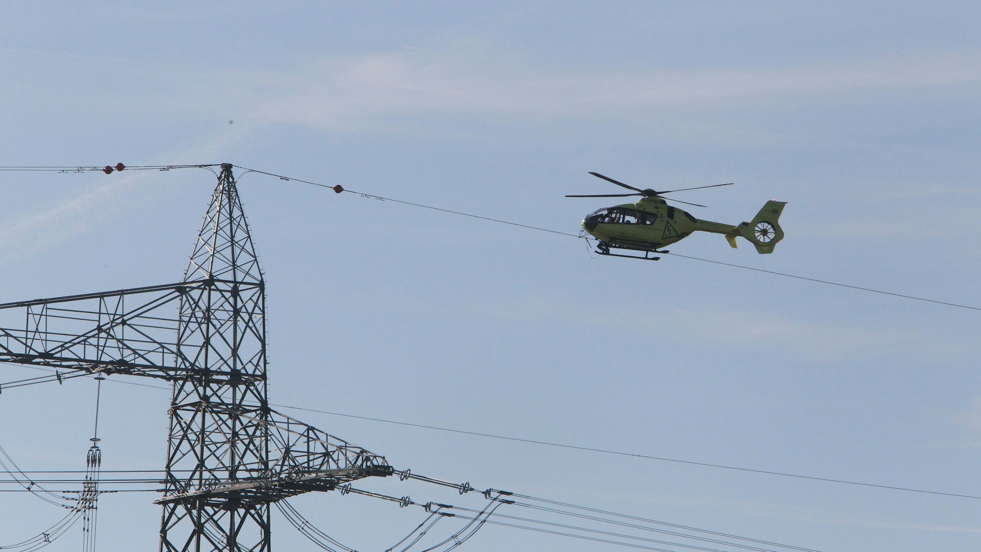 Ein Hubschrauber kreist über einem Strommast.
