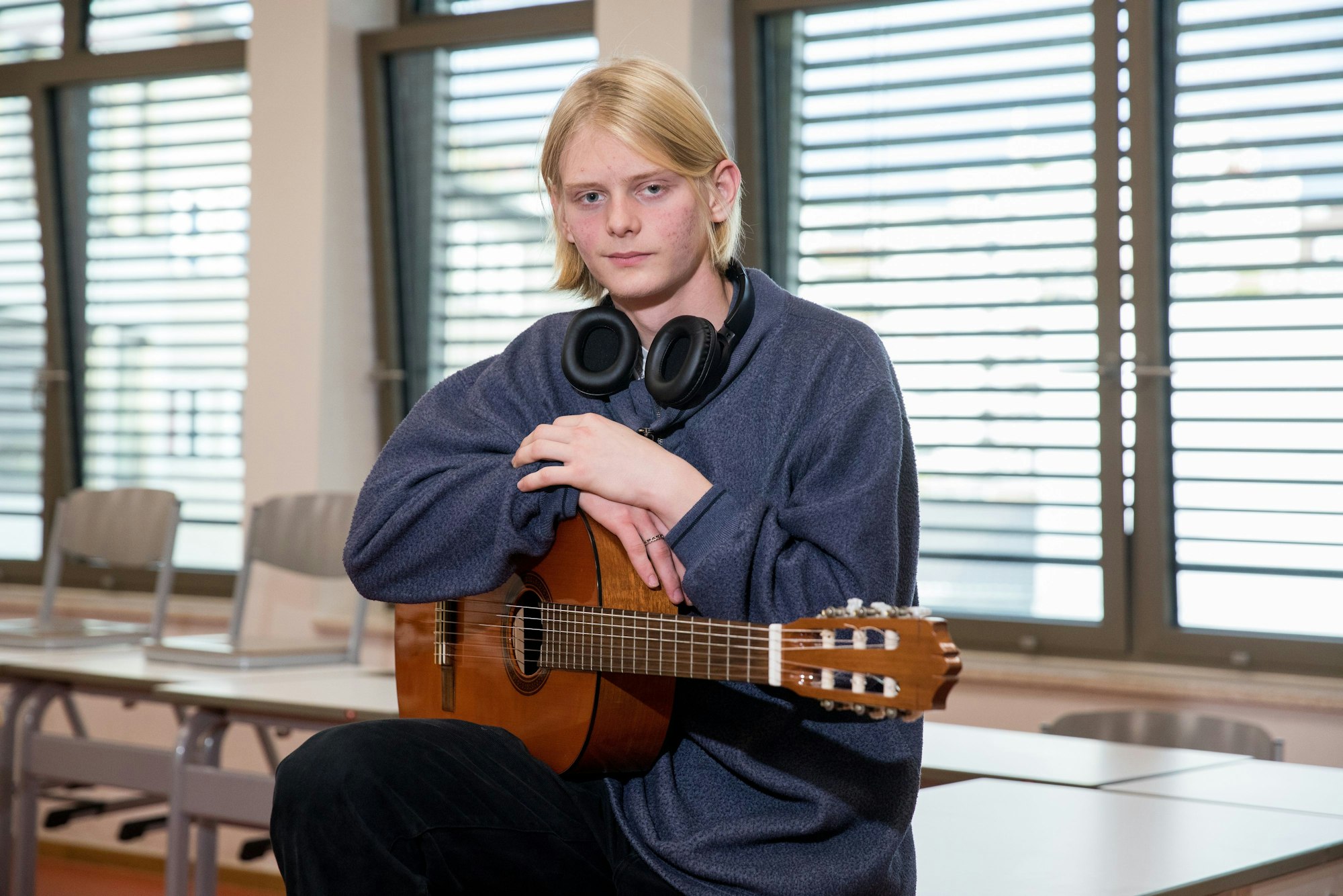 Der 16-jährige Bogdan sitzt mit Gitarre im Klassenzimmer.