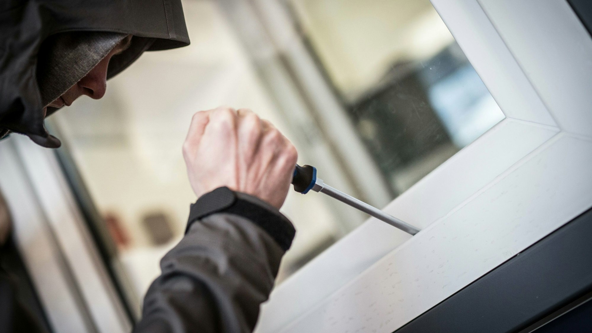 Ein Mann mit einem Werkzeug an einem Fenster.