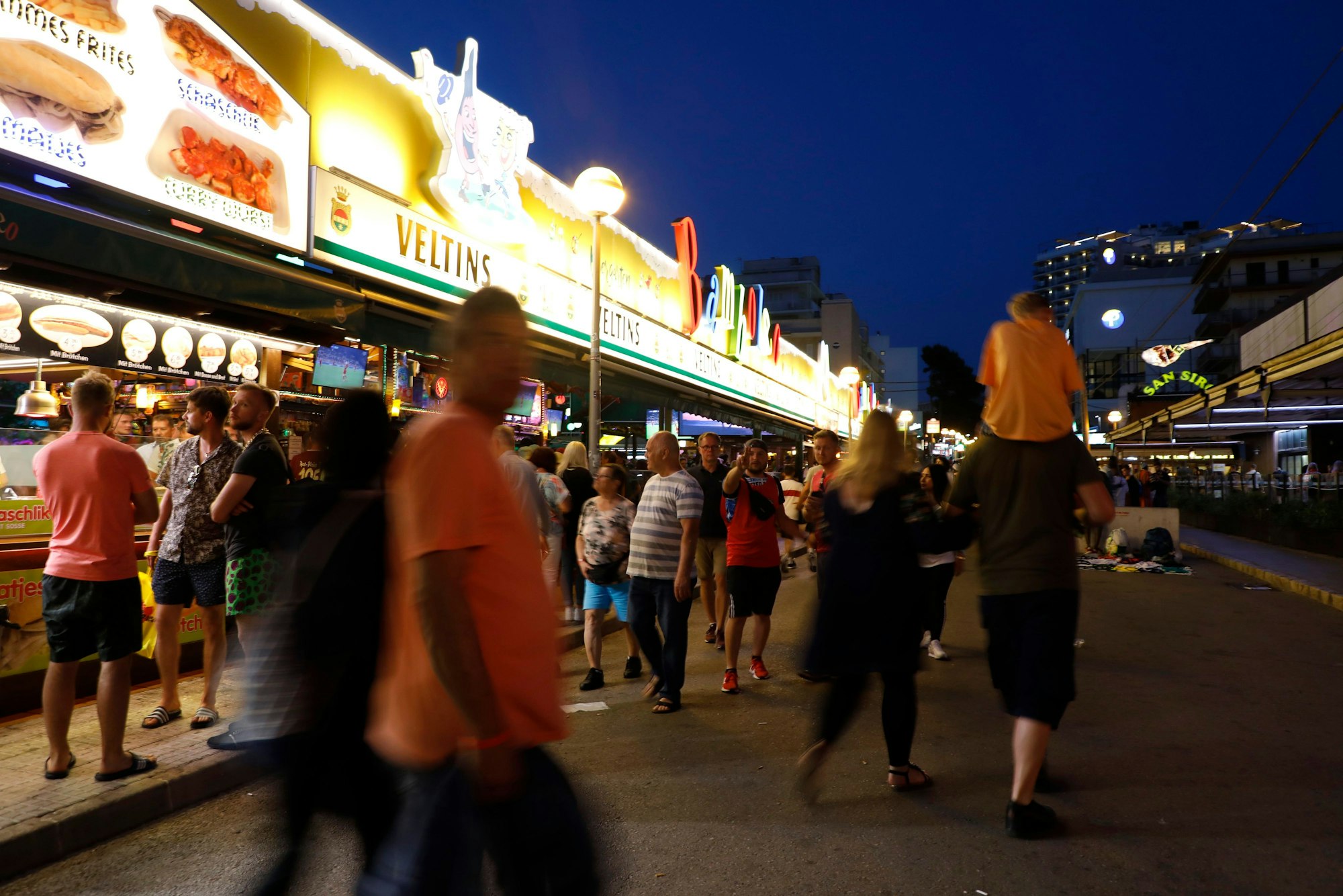 Spanien, Palma: Menschen gehen an der Bar Bamboleo in der Bierstraße am Ballermann vorbei.