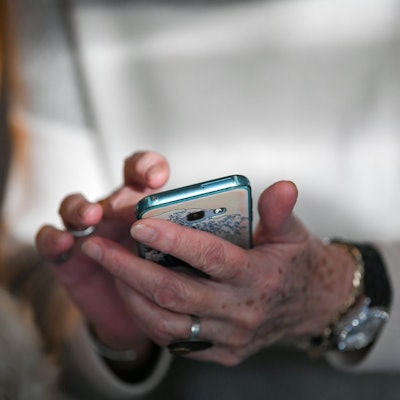 Eine Seniorin hält ihr Smartphone in den Händen.