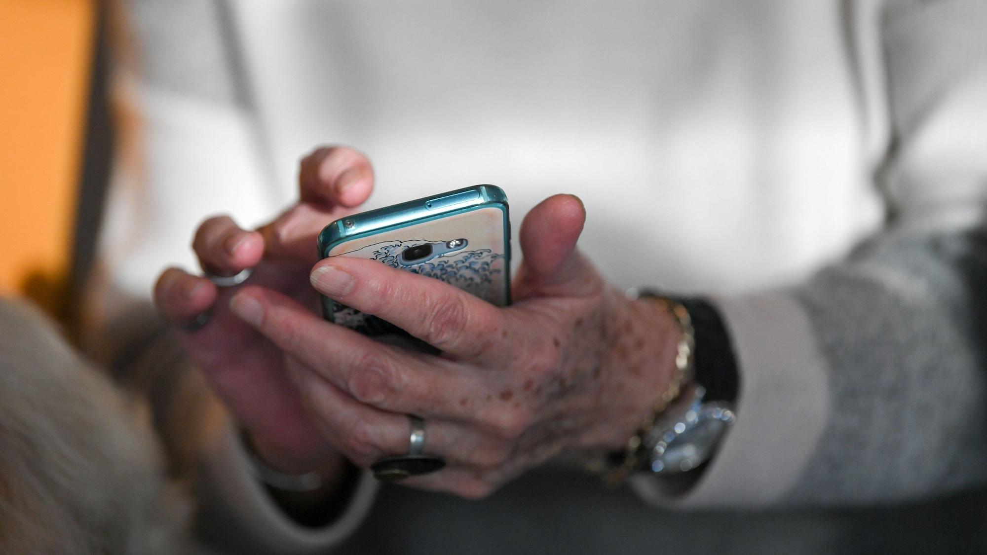 Eine Seniorin hält ihr Smartphone in den Händen.