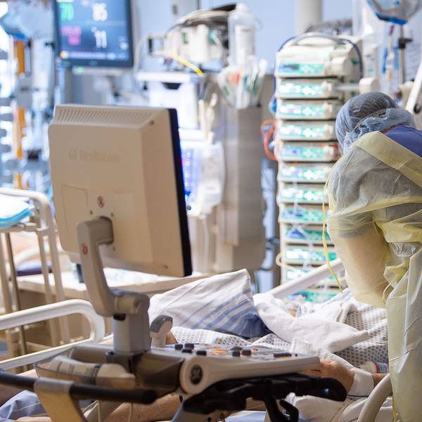 Ein Intensivpfleger steht auf der Intensivstation eines Krankenhauses neben einem Covid-19-Patienten.