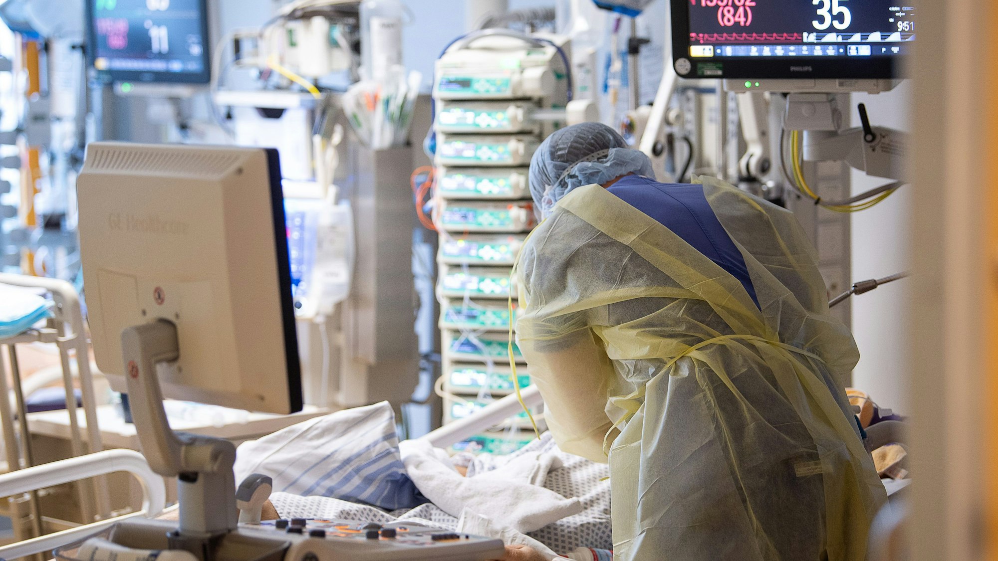 Ein Intensivpfleger steht auf der Intensivstation eines Krankenhauses neben einem Covid-19-Patienten.