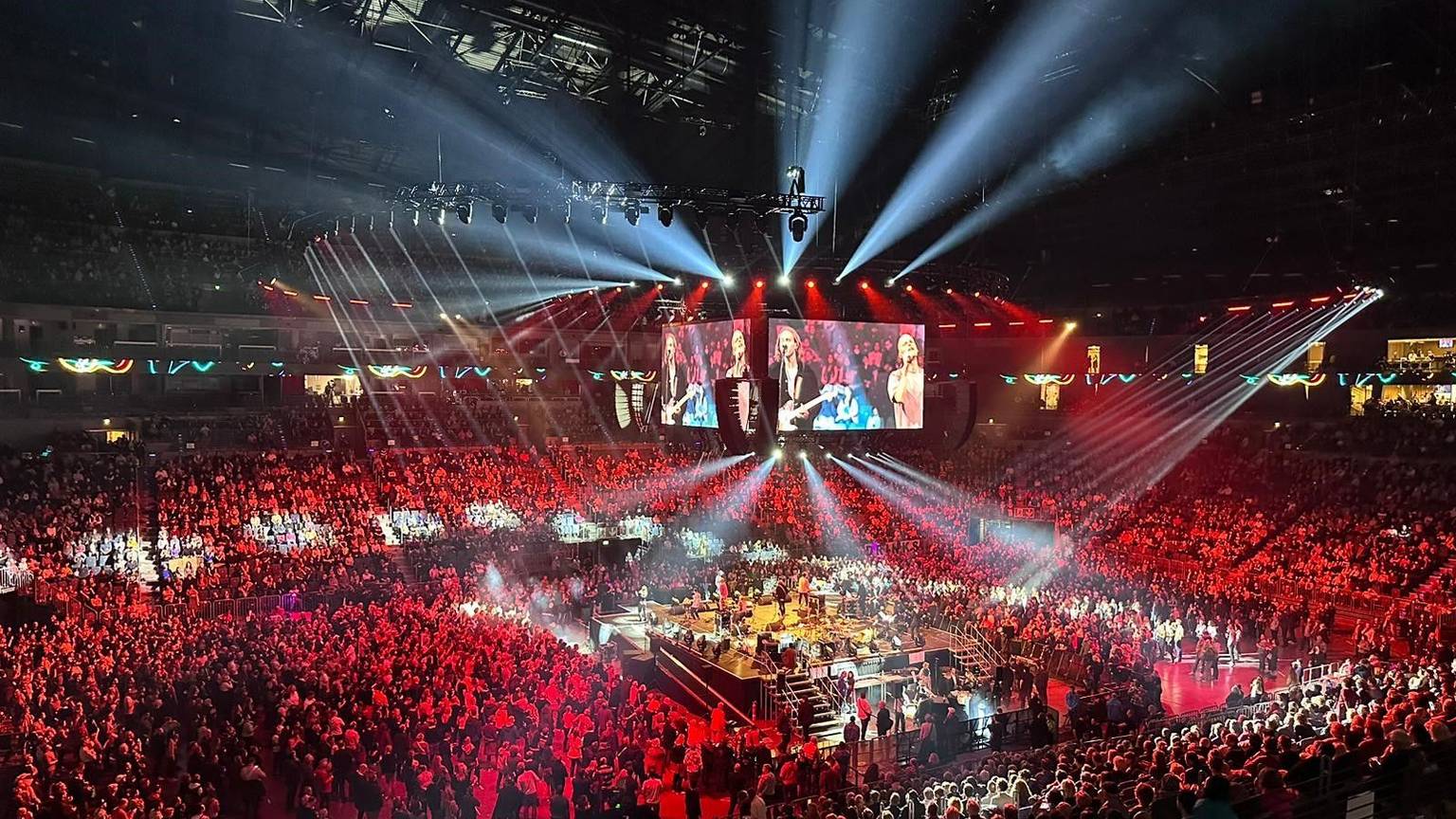 Blick auf den Innenraum in der Arena mit der Bühne in der Mitte, auf der die Band Cat Ballou steht.