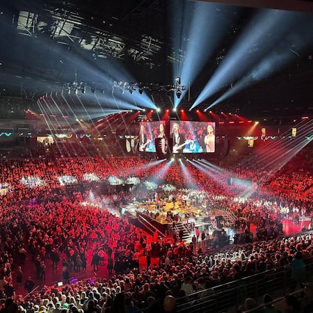 Blick auf den Innenraum in der Arena mit der Bühne in der Mitte, auf der die Band Cat Ballou steht.