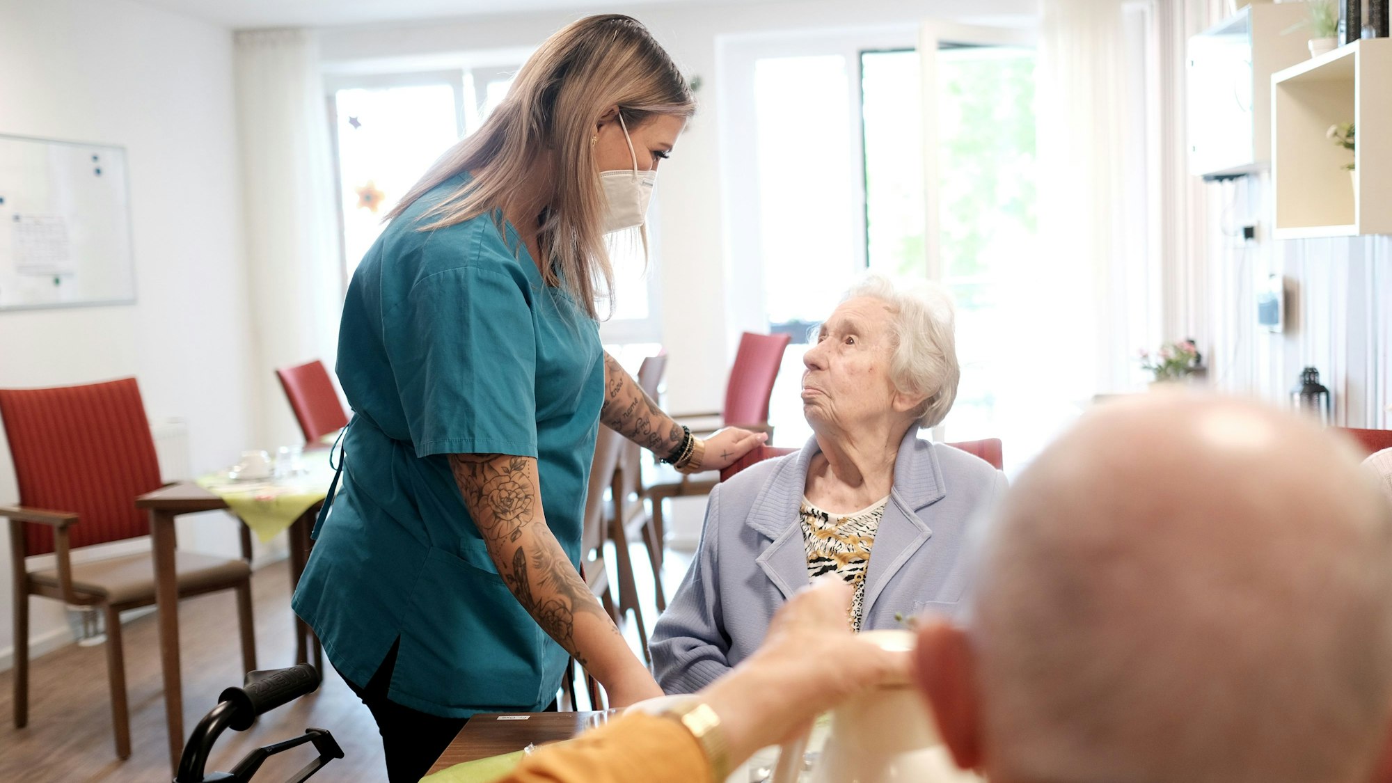 Pflegerin mit Heimbewohnerin und -bewohner (Symbolbild).