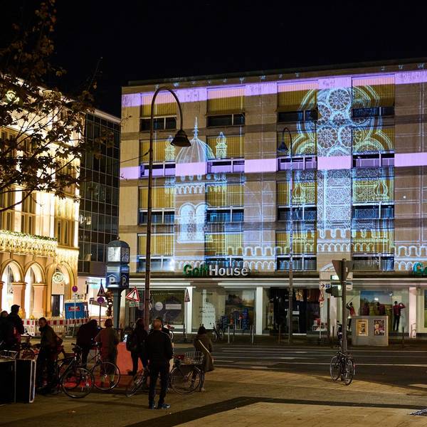 Öffentliche Projektions-Probe der zerstörten Synagoge an der Glockengasse in Köln bei Nacht. Licht ist an eine Hausfassade gestrahlt und zeigt die Synagoge.