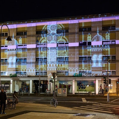 Öffentliche Projektions-Probe der zerstörten Synagoge an der Glockengasse in Köln bei Nacht. Licht ist an eine Hausfassade gestrahlt und zeigt die Synagoge.