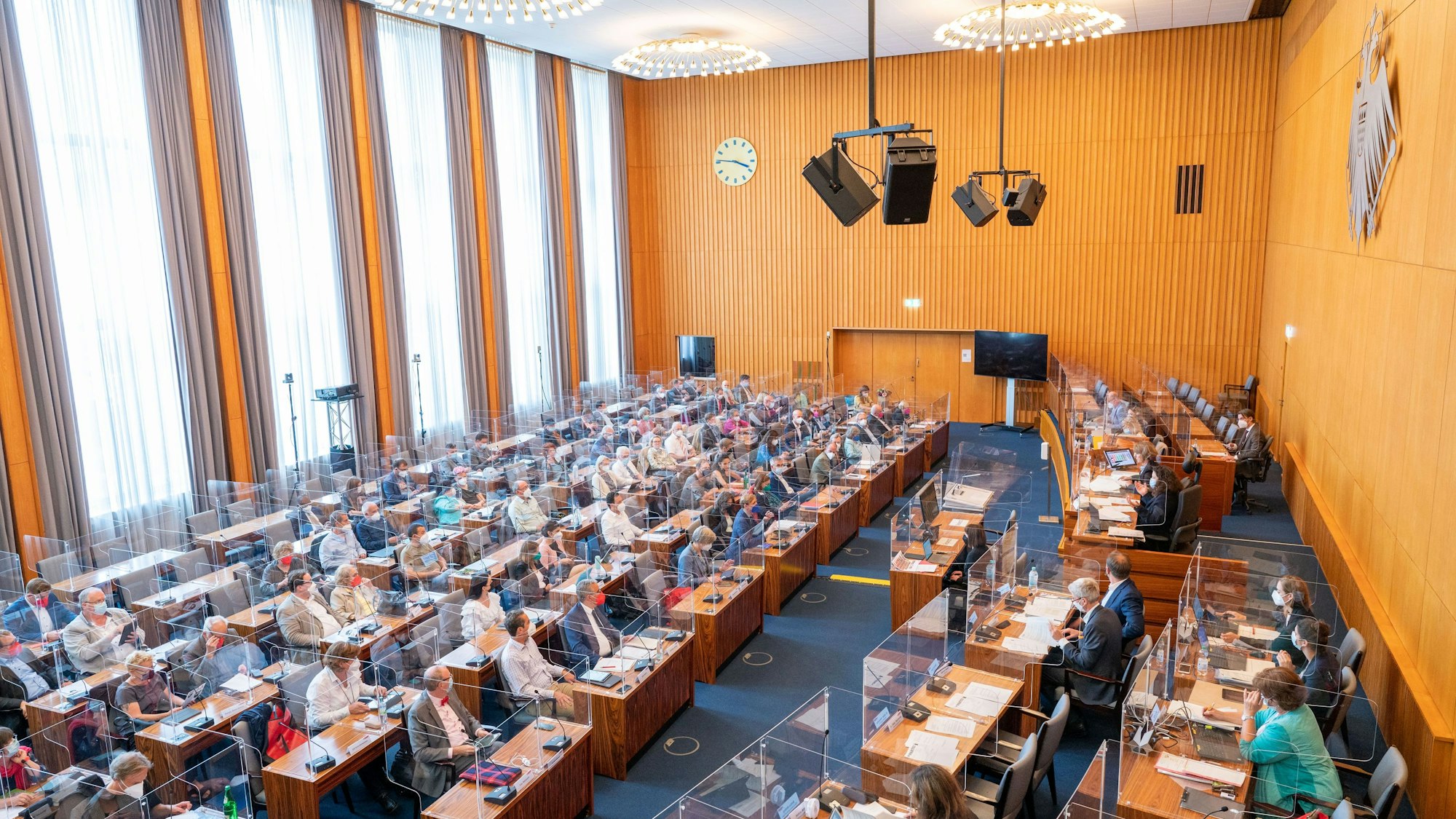 Der Ratssaal im spanischen Bau. Zahlreiche Stadträte sitzen an ihren Plätzen und verfolgen die Kölner Ratssitzung hinter Glasscheiben.