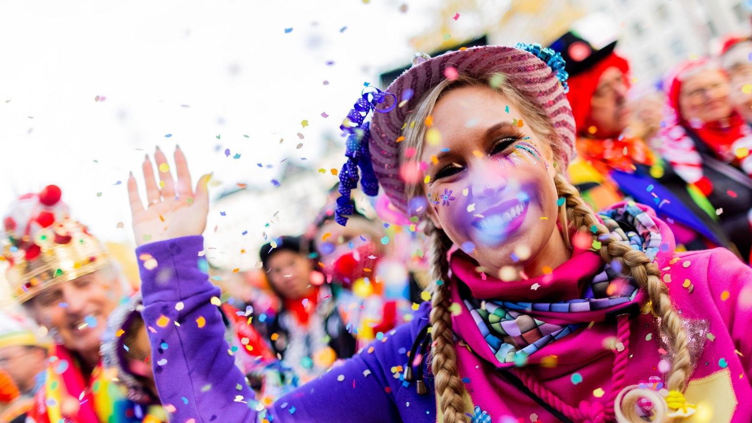 Eine verkleidete Frau wirft Konfetti in die Luft.