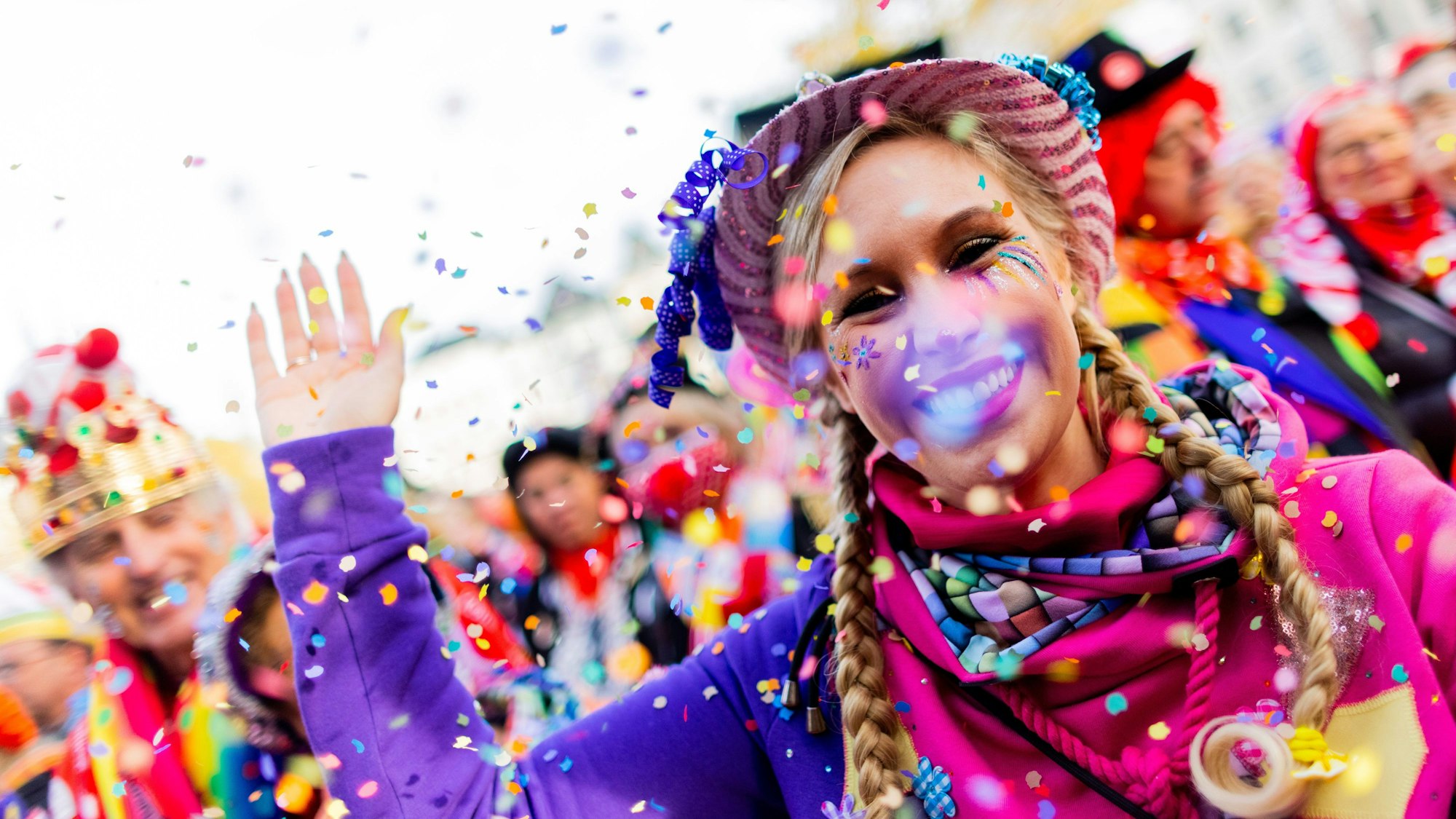 Eine verkleidete Frau wirft Konfetti in die Luft.