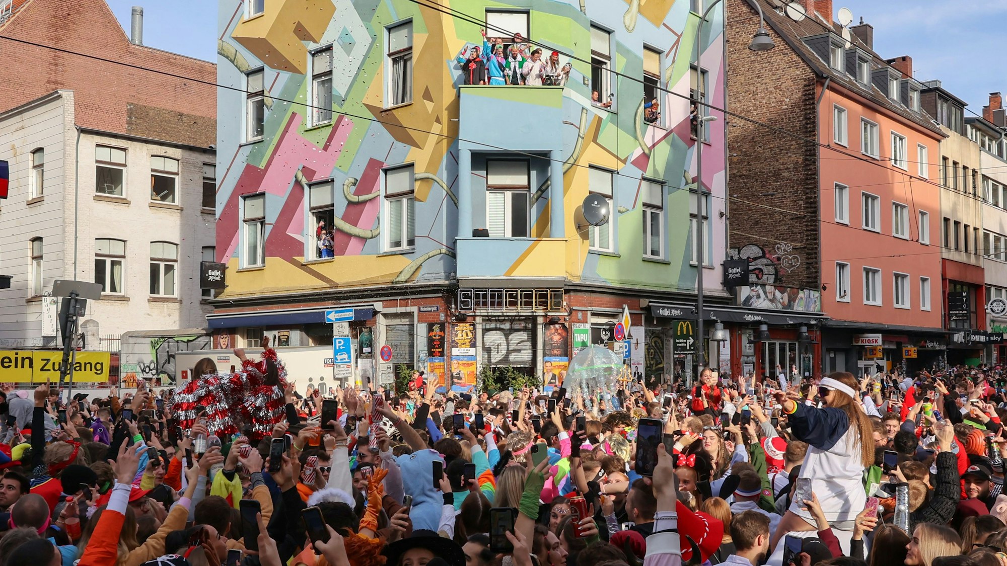 Menschen strecken die Arme in die Höhe. Im Hintergrund ist das Gebäude der Kneipe Stiefel zu sehen.