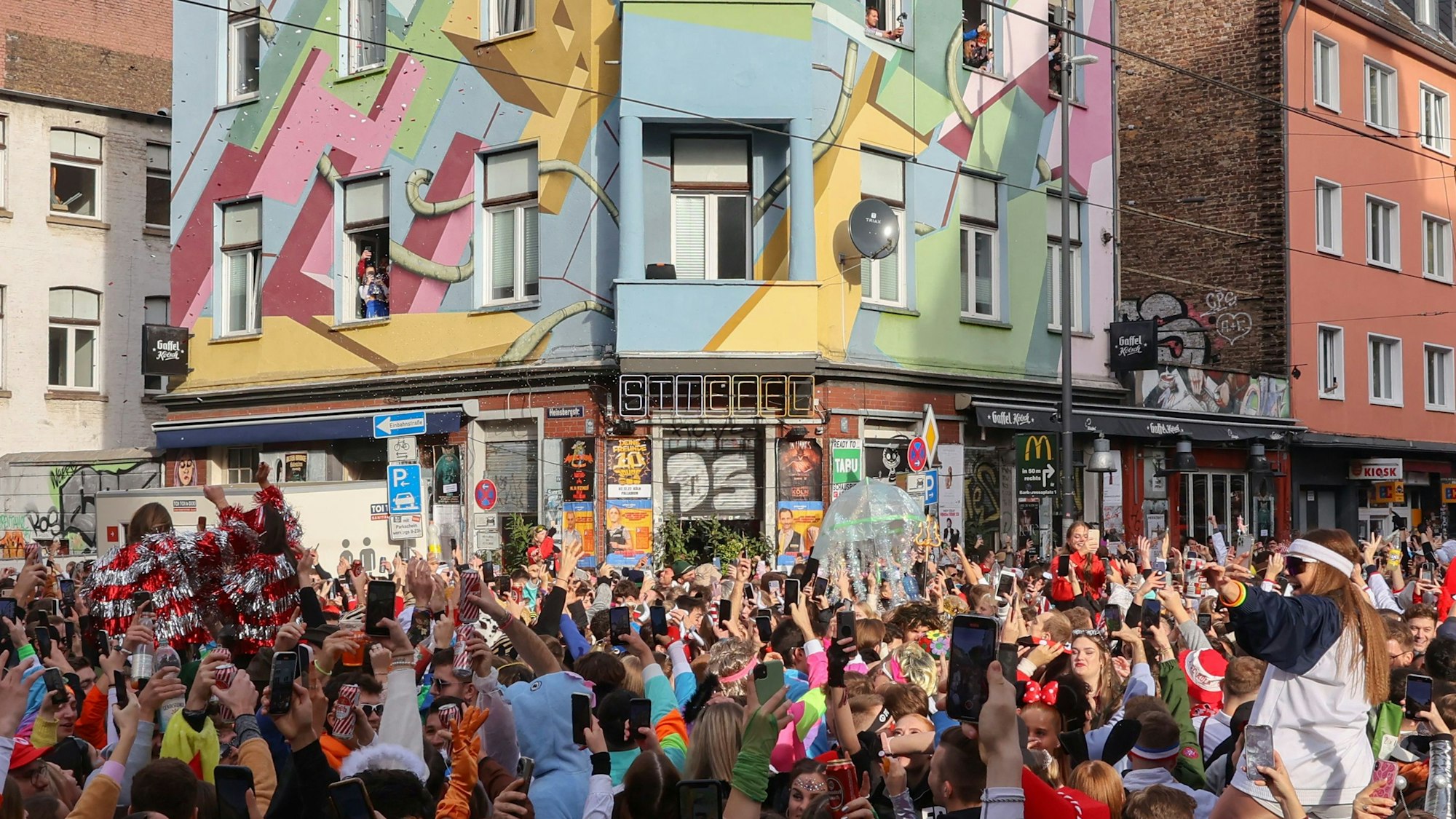 Die Zülpicher Straße, mit Blickrichtung auf die Kneipe "Der Stiefel" am 11.11. zum Karnevals-Sessionsauftakt. An der Kreuzung hat sich eine große Menge junger, verkleideter Menschen angesammelt.