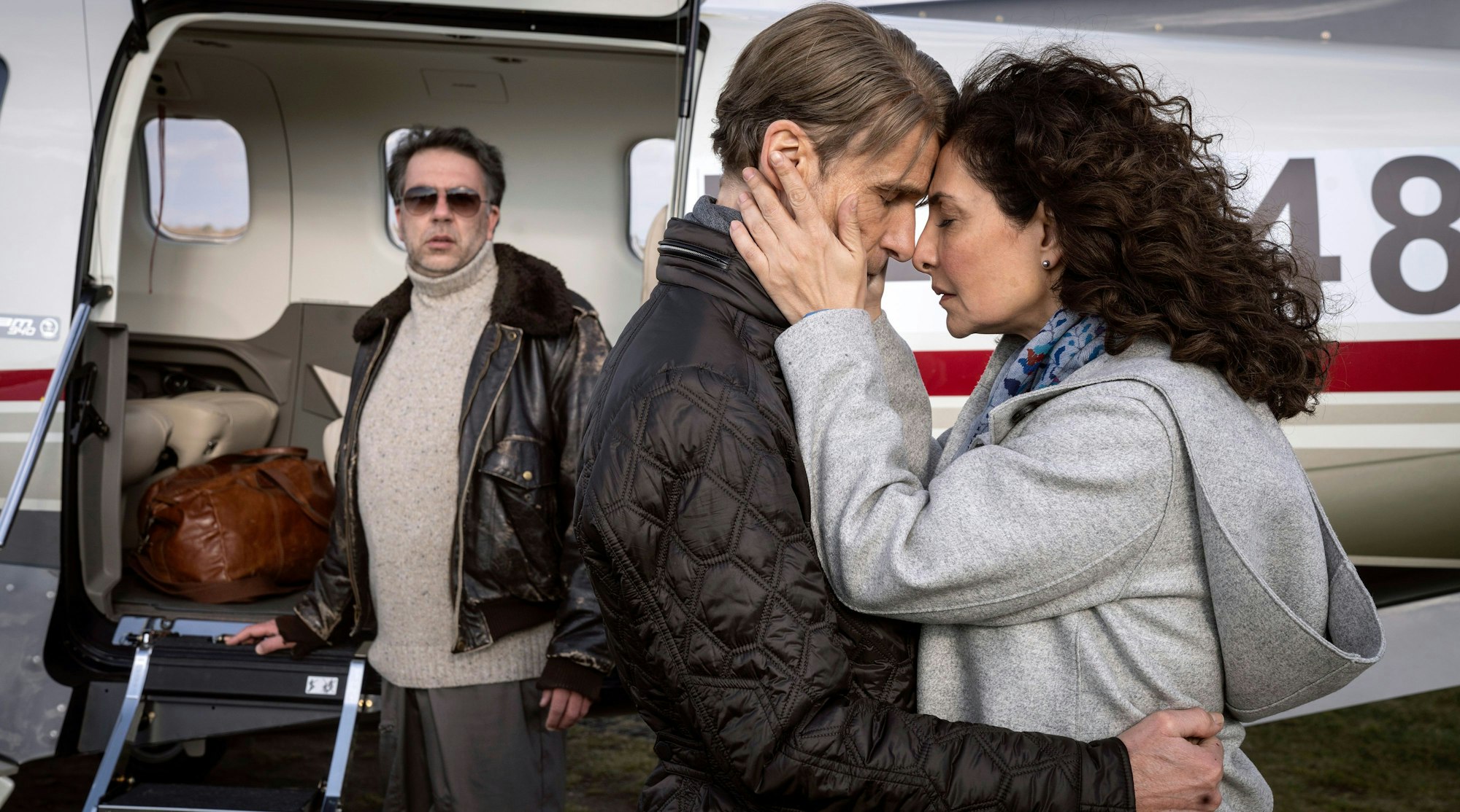 Friedhelm und Veronika Fabian lehnen den Kopfeinander, im Hintergrund ein Flugzeug und ihr Pilot.