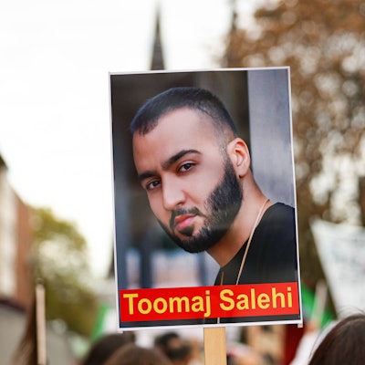 Ein Demonstrierender hält ein Schild mit dem Portrait des iranischen Rapper Toomaj Salehi bei einer Demonstration in Köln in die Höhe.