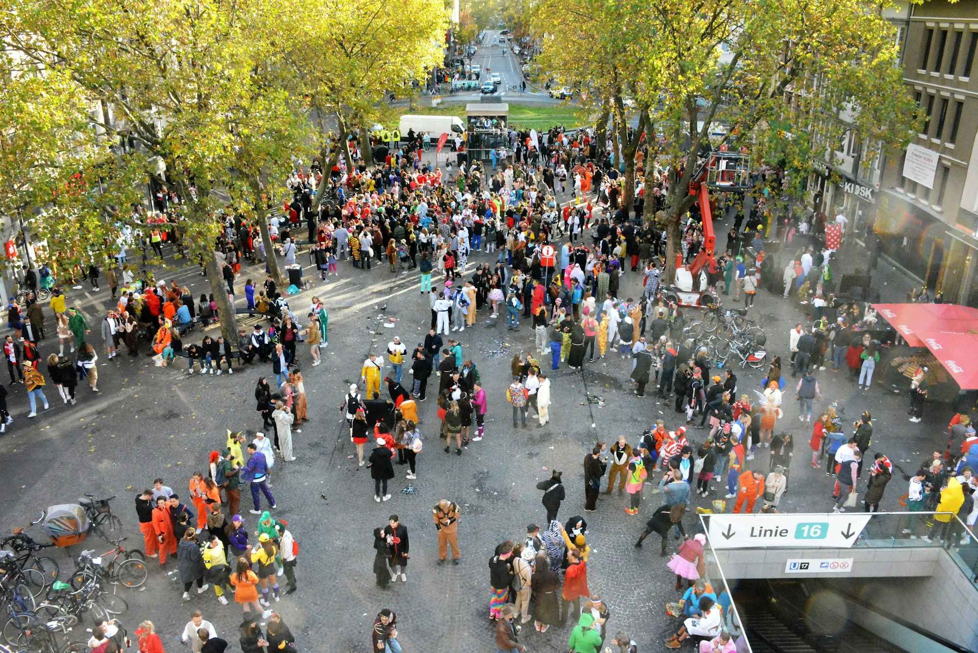 Gruppen von Kostümierten stehen auf dem Chlodwigplatz am Nachmittag gesehen vom Wehrgang der Severinstorburg.