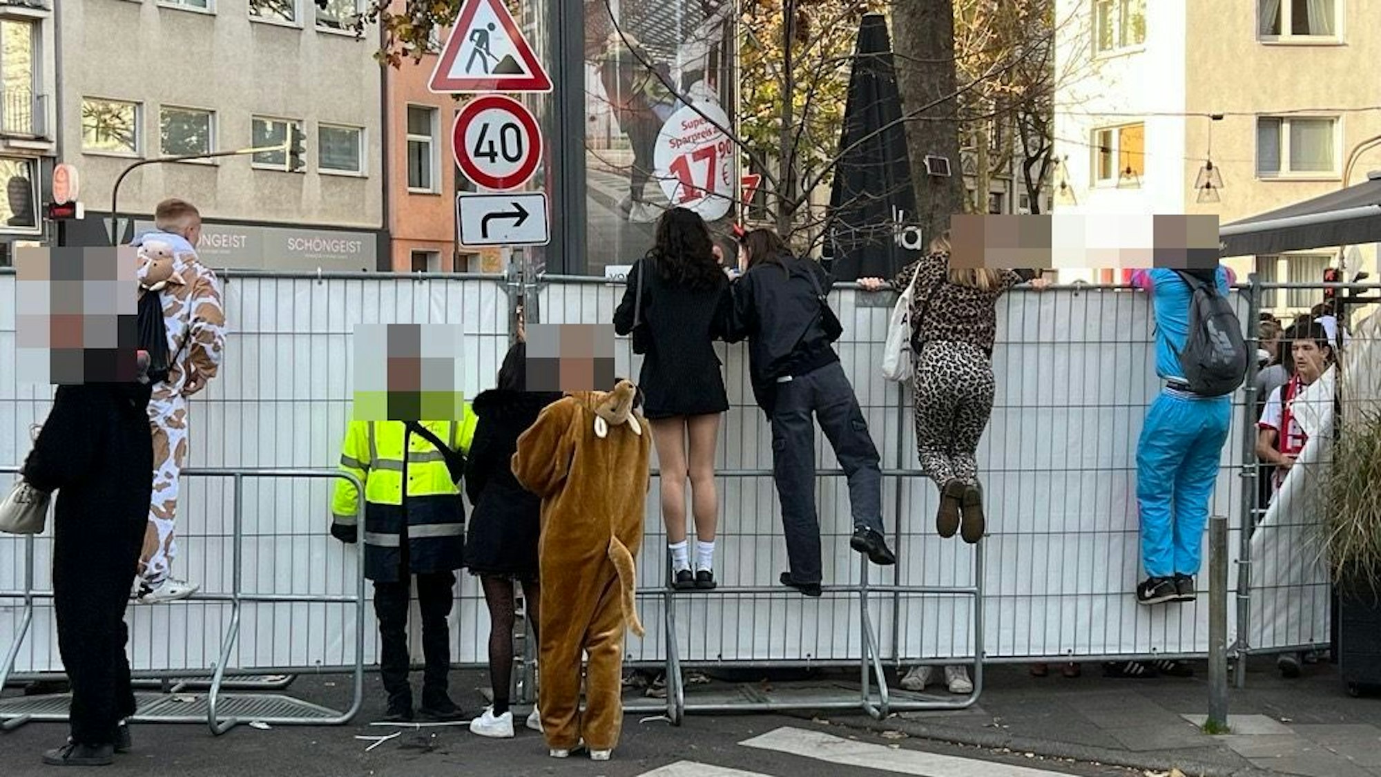 Menschen klettern über einen Bauzaun.