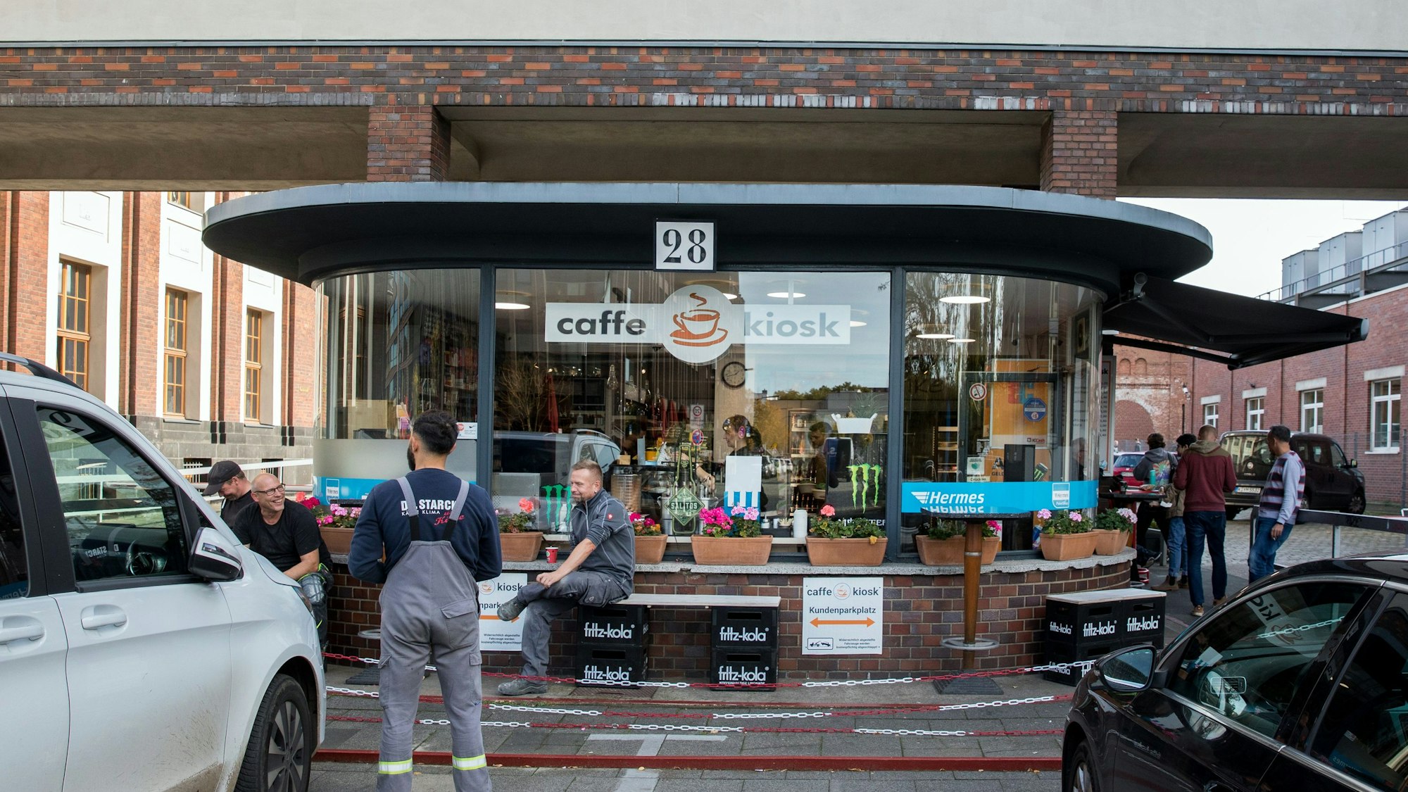 Drei Arbeiter machen Pause vor dem Caffe Kiosk in einem ehemaligen Pförtnerhäuschen in der Schanzenstraße in Köln-Mülheim.