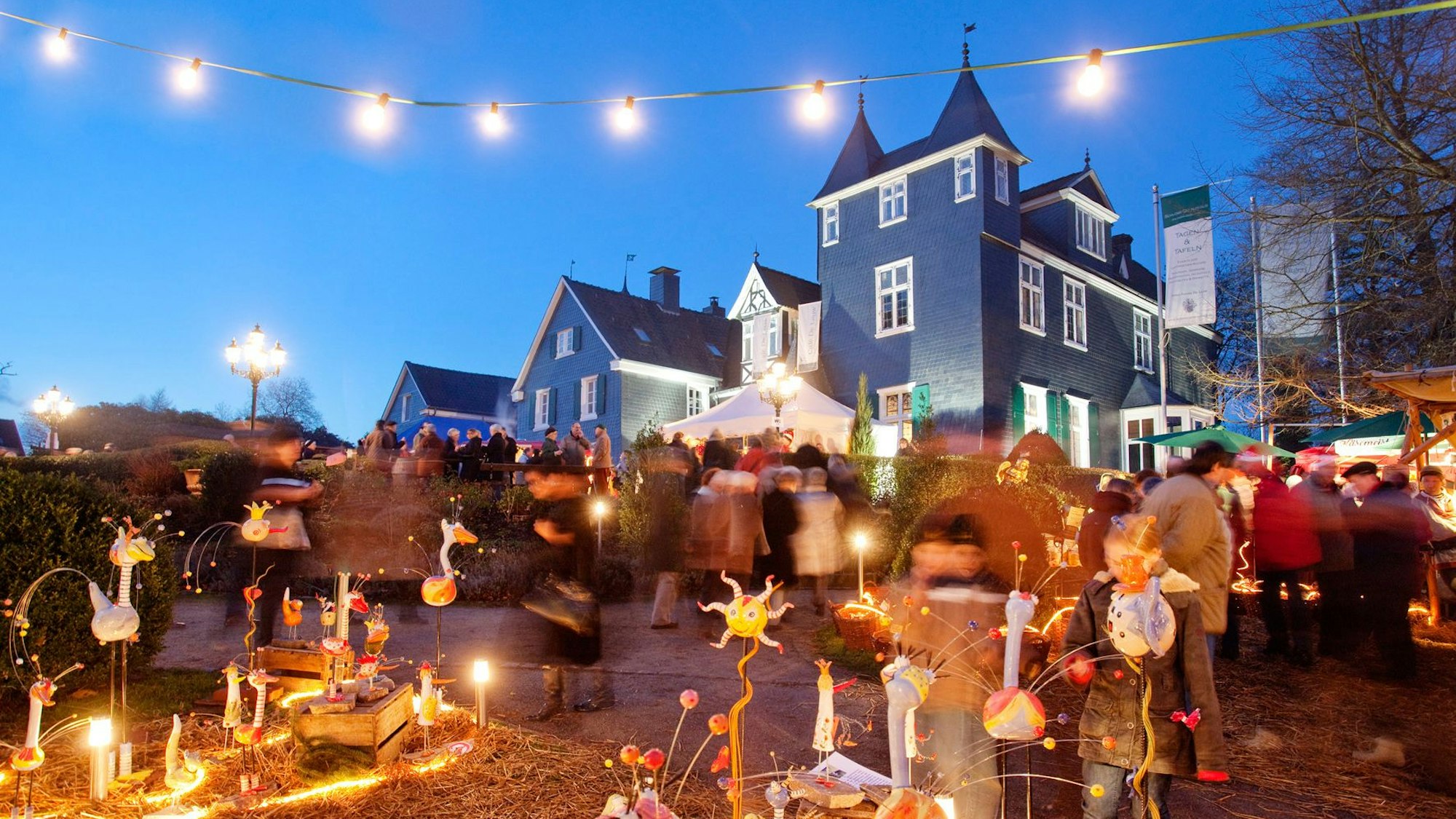 Menschen und Weihnachtslichter vor Burganlage in Solingen.