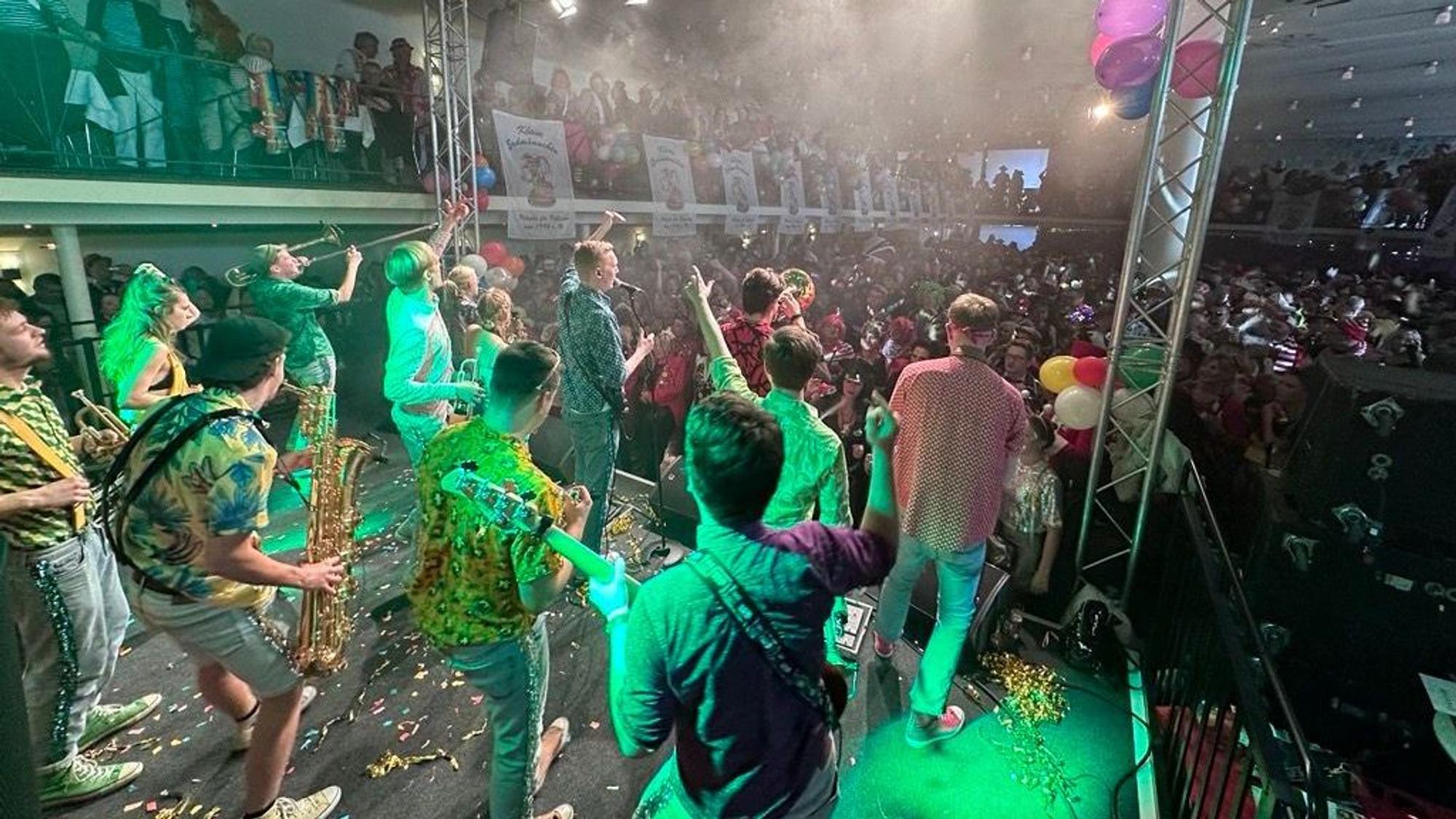 Auf der Bühne im Gürzenich feiert eine Musikkapelle mit den zahlreichen Verkleideten im Publikum.