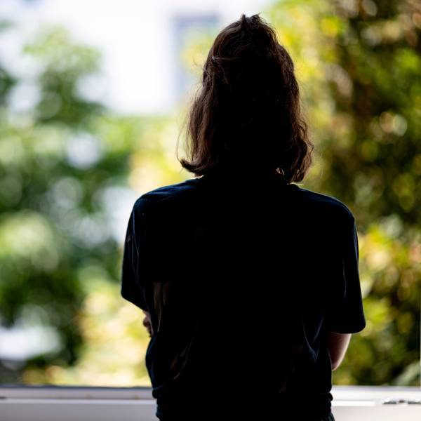 Eine Frau steht in ihrer Wohnung an einem Fenster
