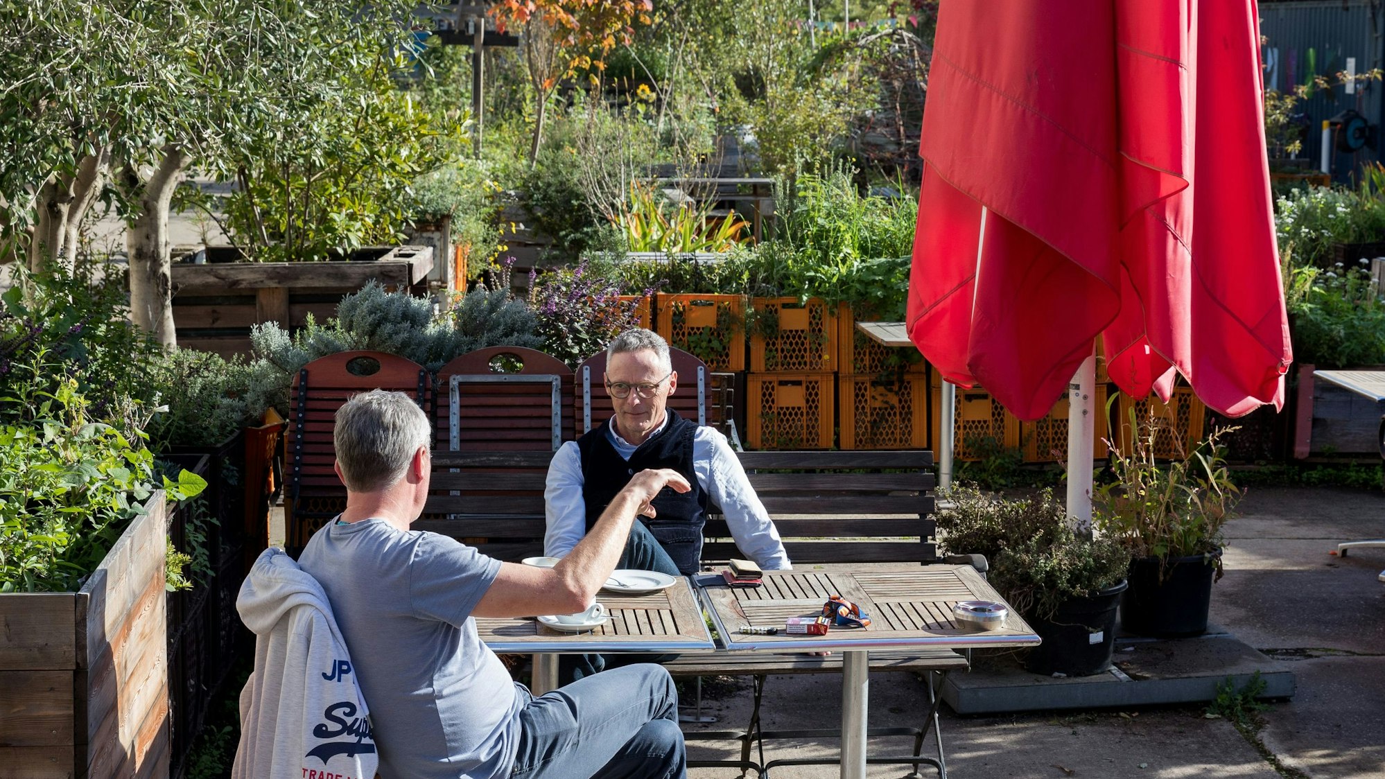 Jörg Ulrich und Volker Klein sitzen im Garten des Restaurants Offenbach am Carlsgarten in Köln-Mülheim.