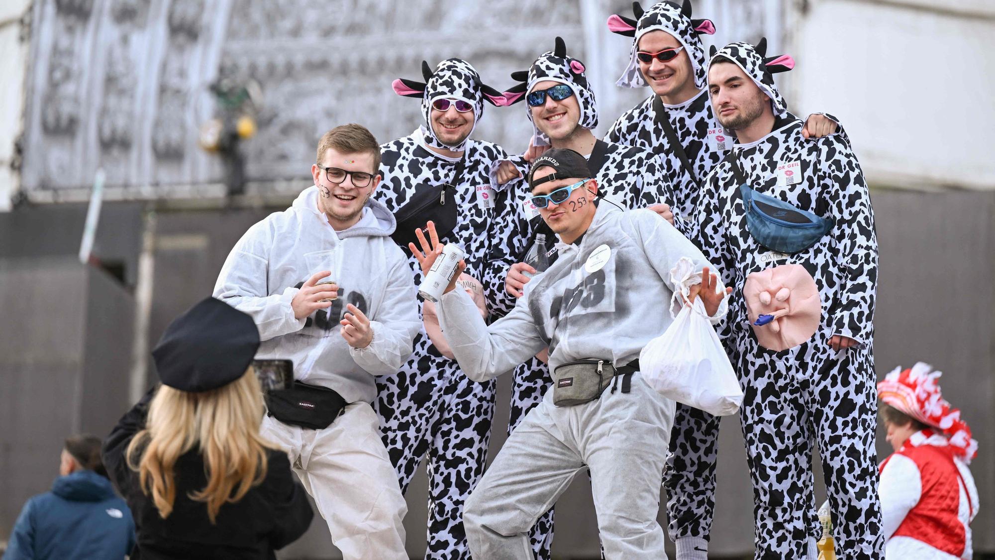 Mehrere Männer sind als Kühe verkleidet und lassen sich von einer Frau vor dem Kölner Dom fotografieren.