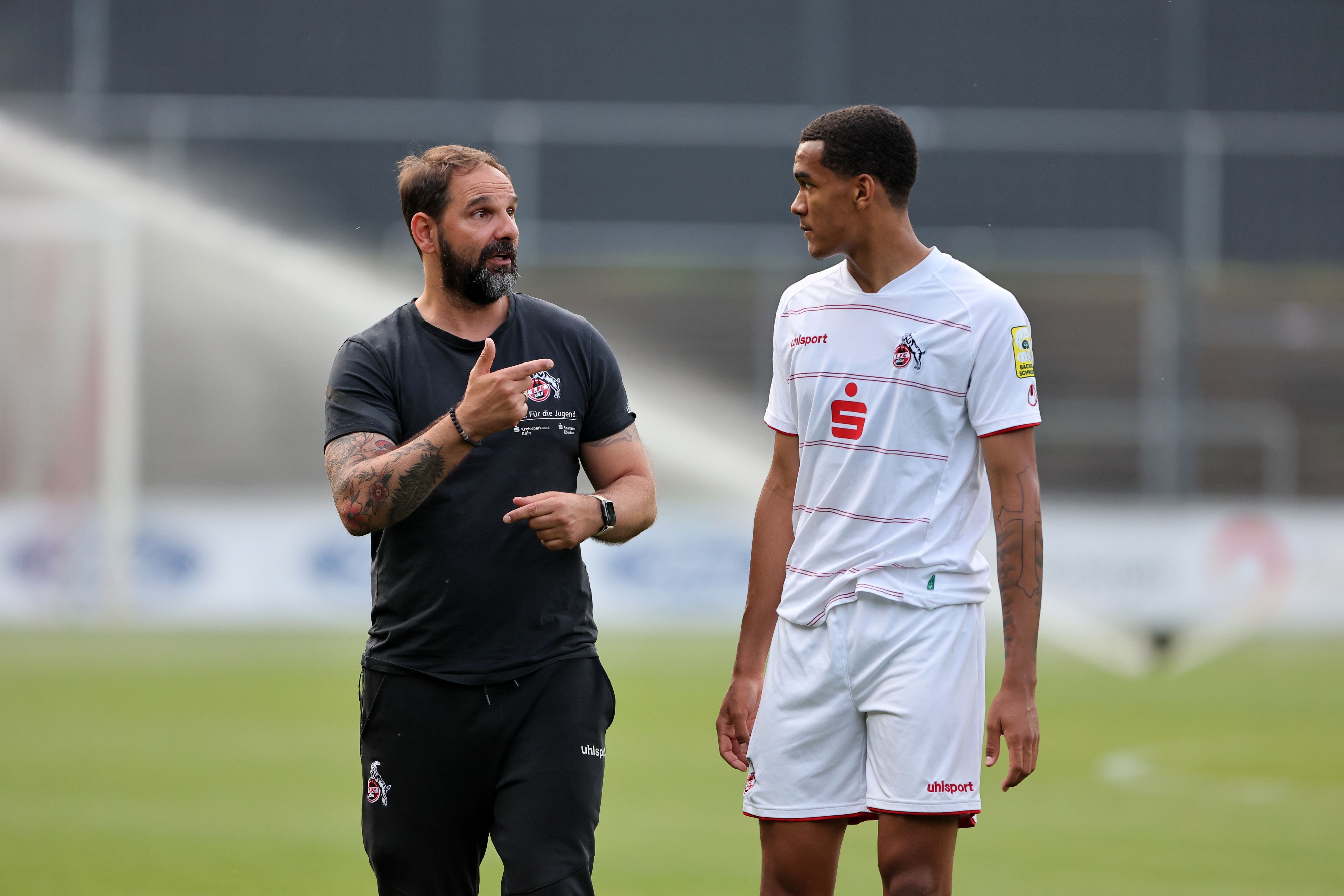 Ein Fußballtrainer (links im Bild) bespricht sich mit seinem Spieler.