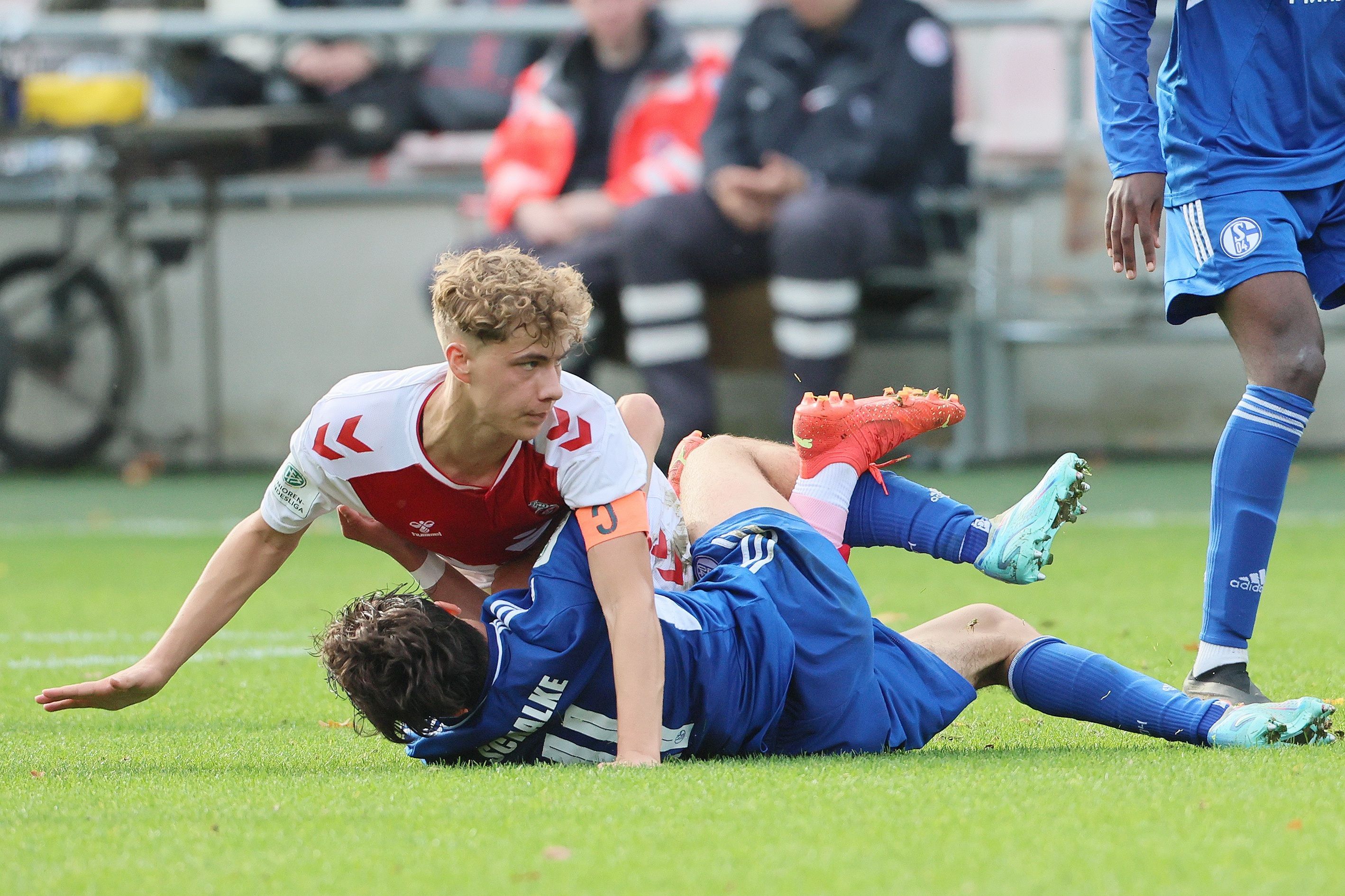 Zwei Fußballspieler liegen während eines Zweikampfs übereinander auf dem Boden.