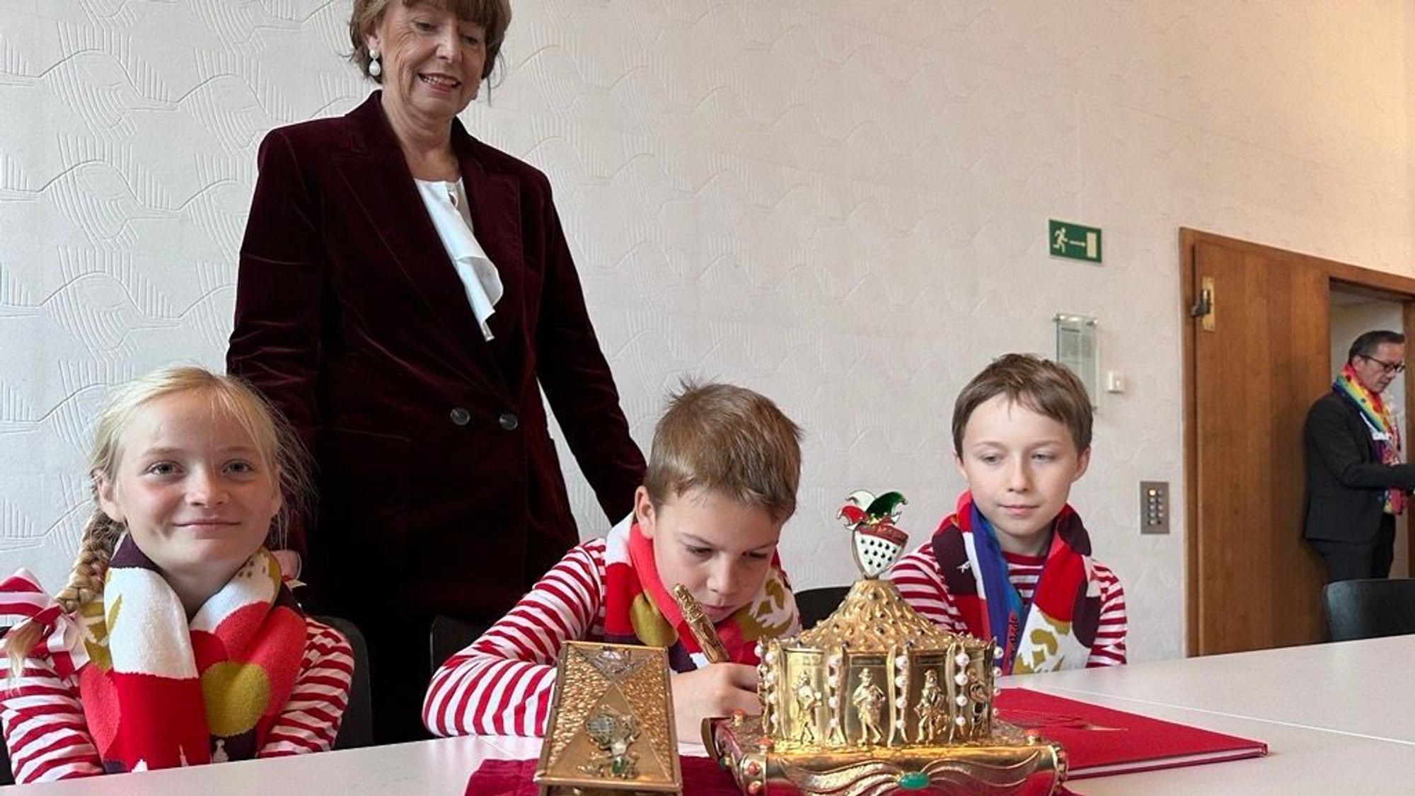 Das Kinderdreigestirn unterschreibt im Rathaus den Vertrag der Stadt.