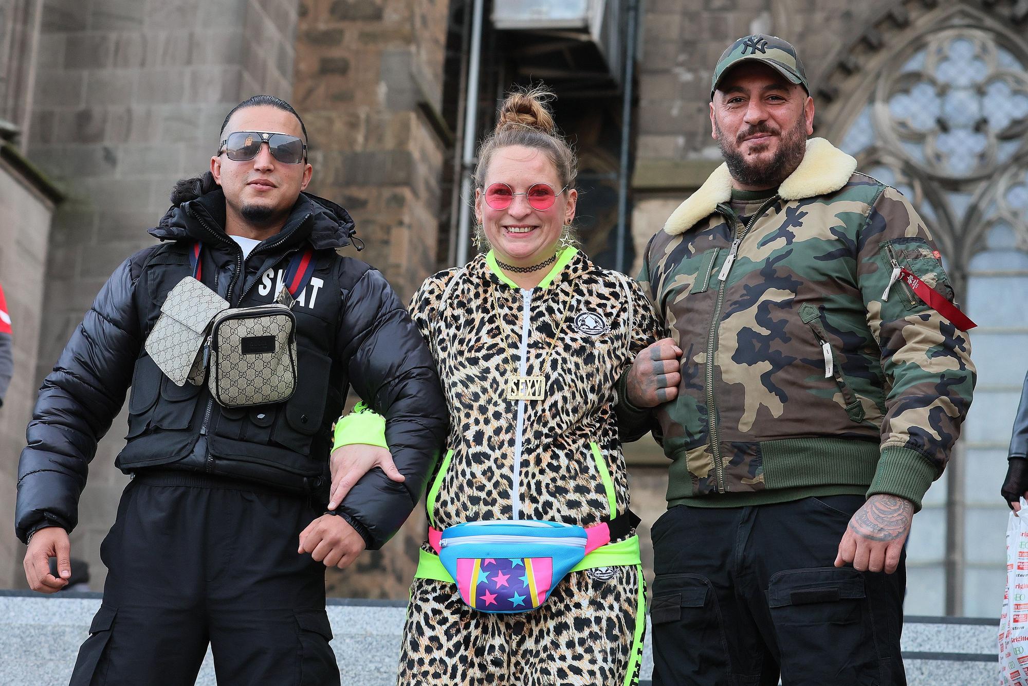Sessionsauftakt Kölner Karneval: Lara im Leoparden-Anzug mit Yusuf in „Swat“-Weste und Waso in Camouflage-Jacke vor dem Dom.