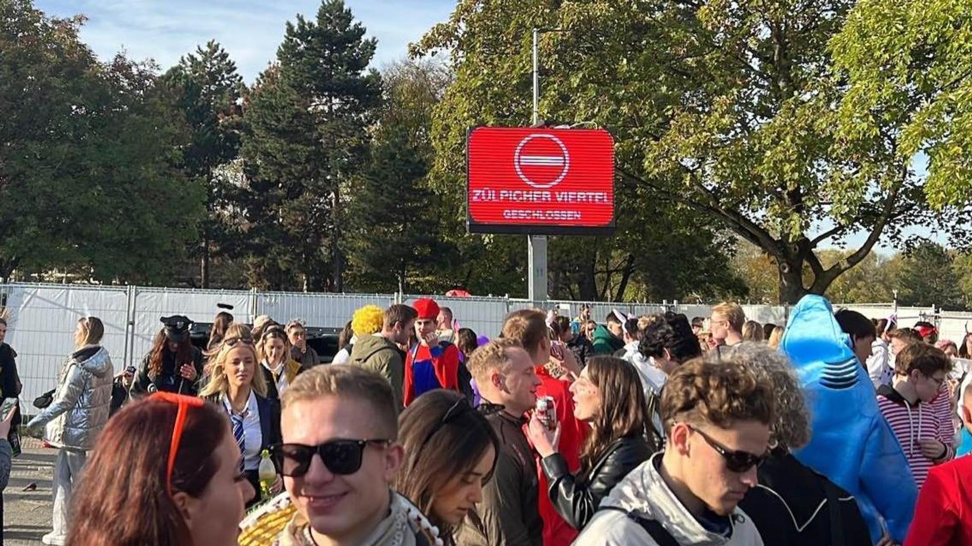 Schild mit der Aufschrift „Einbahnstraße“, davor sind Feiernde.