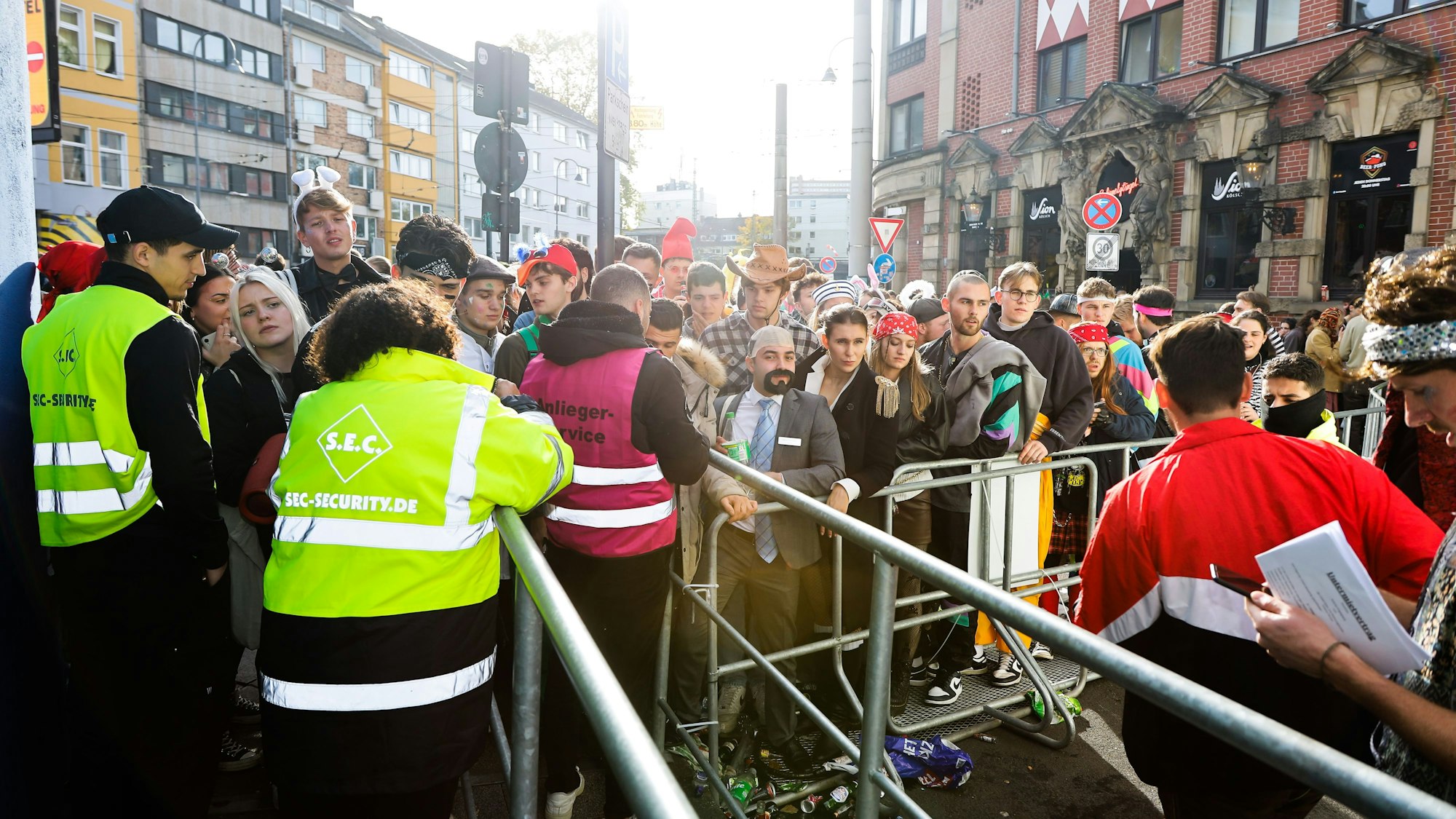 Die Zülpicher Straße am 11.11. Viele Verkleidete stehen vor einem Zugang, der von Securityleuten kontrolliert wird.