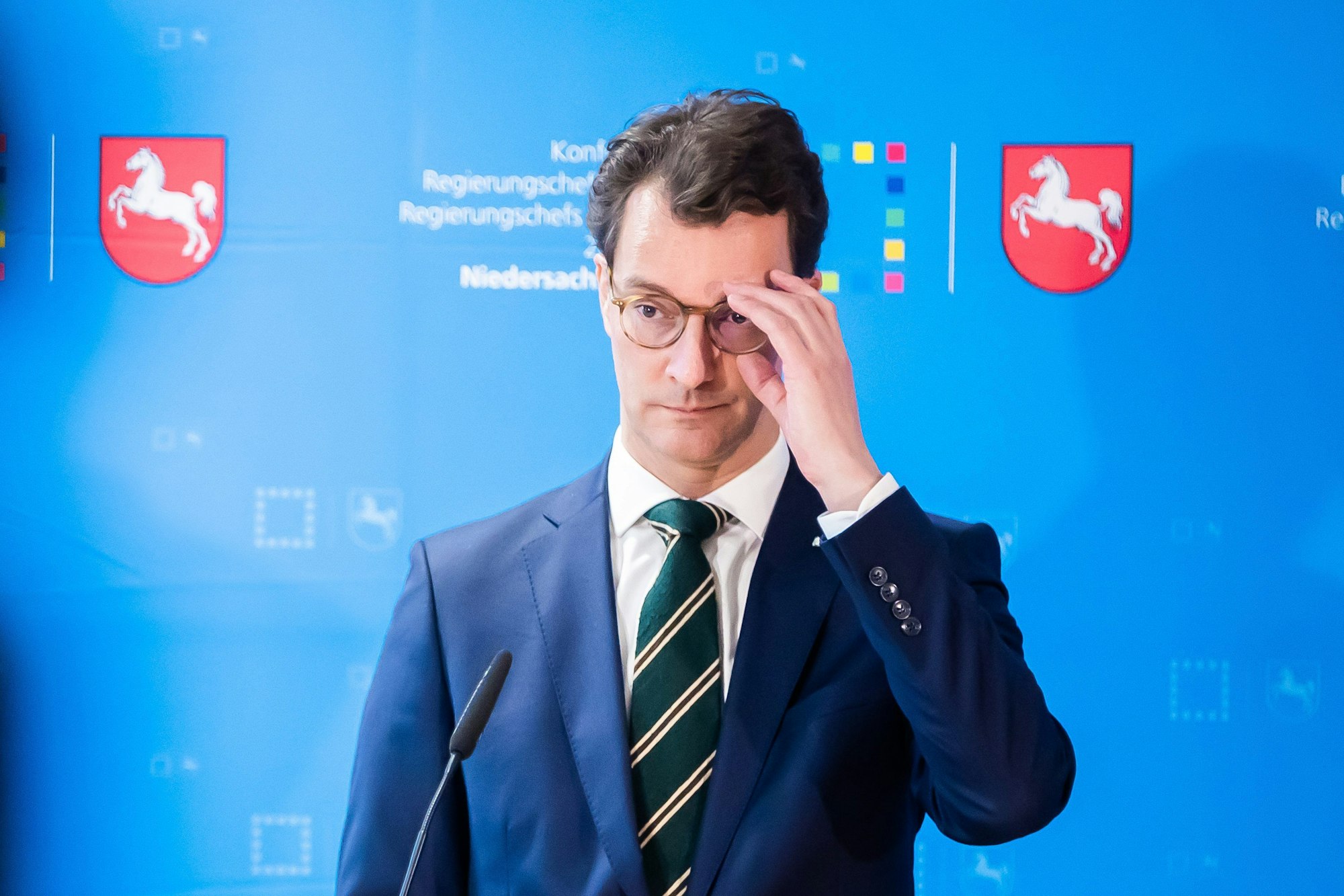 Hendrik Wüst (CDU), Ministerpräsident von Nordrhein-Westfalen,steht vor einem Mikrofon und fasst sich an die Brille.