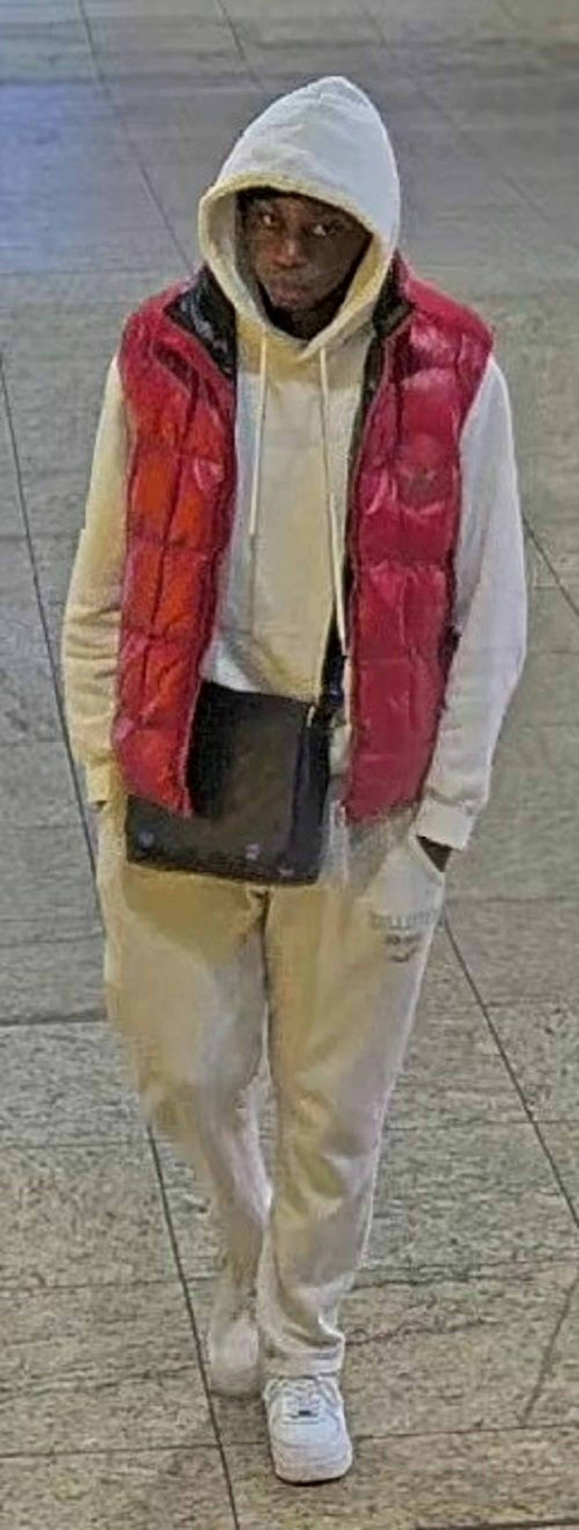Einer der Tatverdächtigen trägt eine weiße Trainingshose, einen Hoodie, Sportschuhe, eine rote Weste
