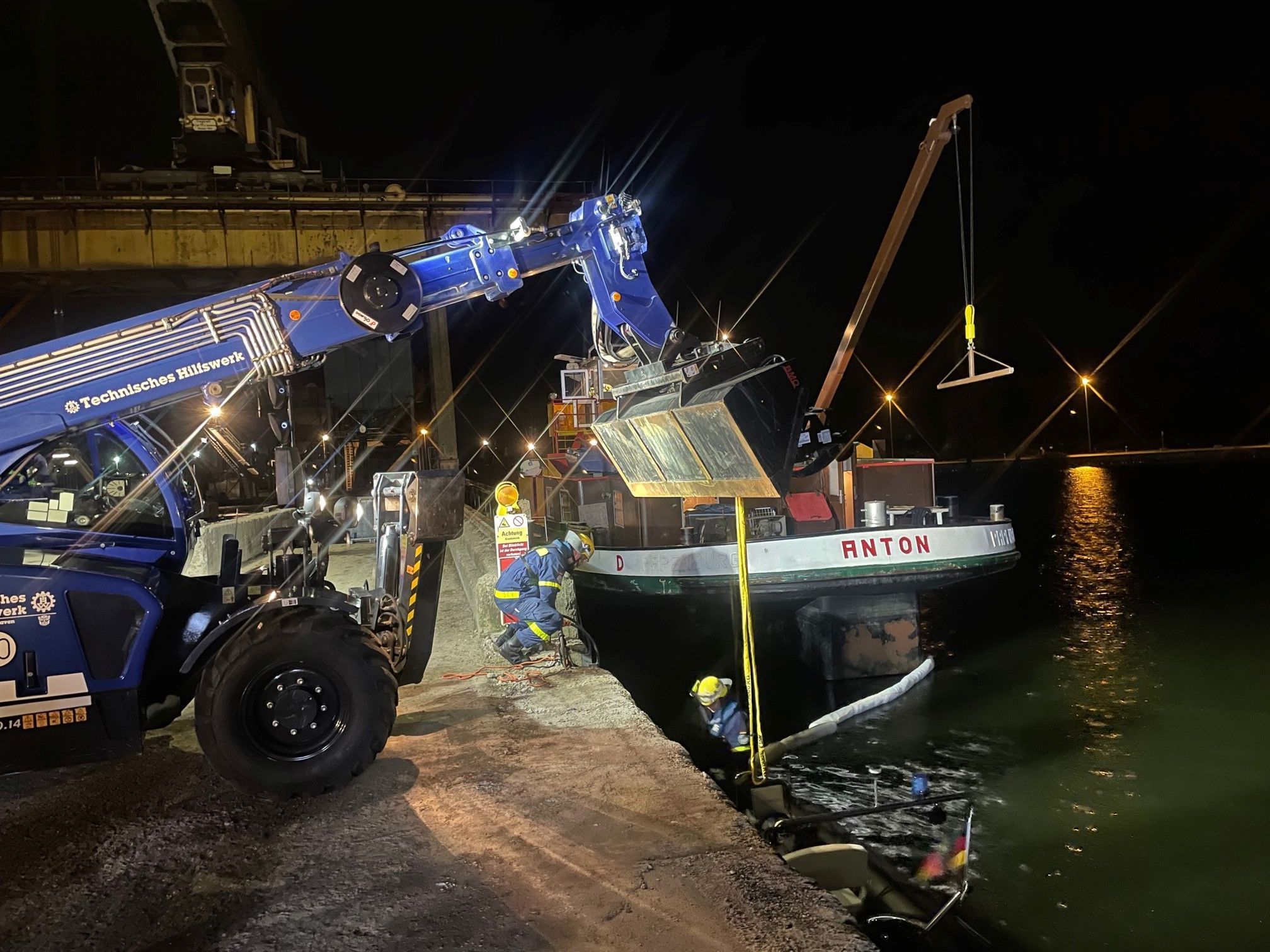 Einsatzkräfte und ein Spezialfahrzeug stehen rund um das havarierte Schiff „Anton“.