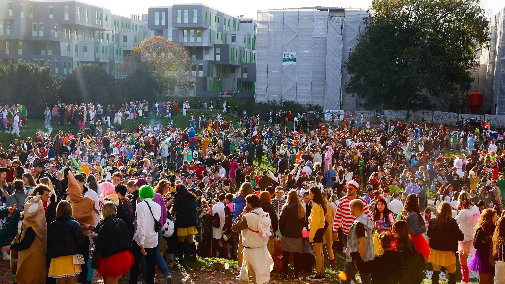 Auf der Uni-Wiese stehen zahlreiche Feiernde, die bunt kostümiert sind.