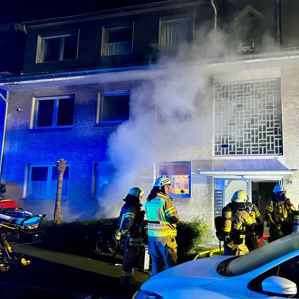 Aus einem Haus steigt Qualm auf. Vor dem Haus stehen mehrere Feuerwehrleute.