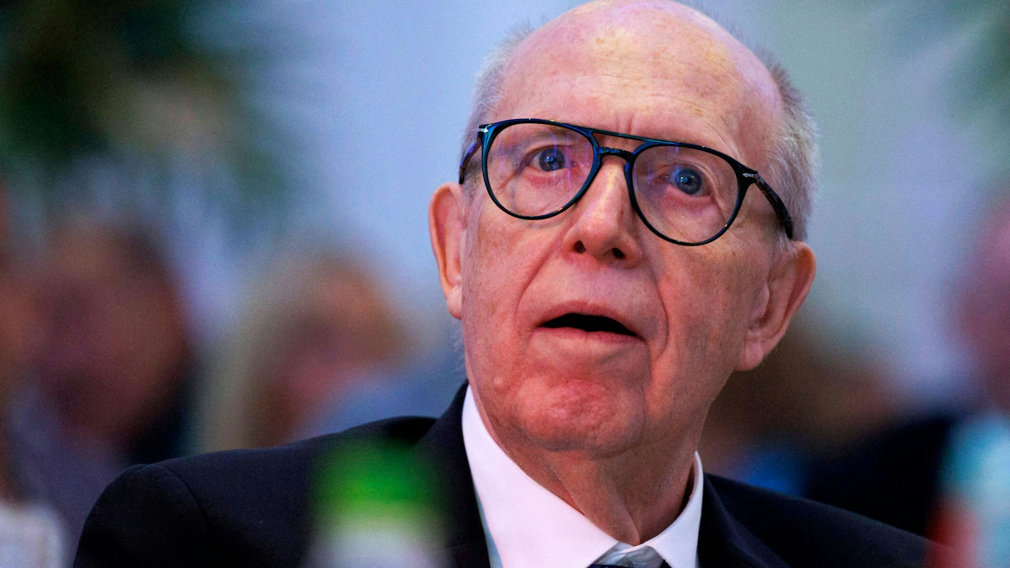 Reiner Calmund sitzt bei einer Benefiz-Gala in der Kölner Flora an einem Tisch und schaut in Richtung Bühne.