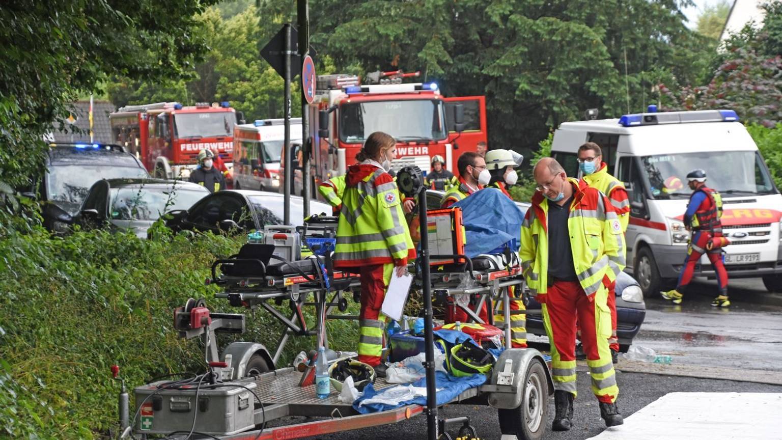 Uniformierte Helfer der DLRG und des DRK stehen mit ihren Fahrzeugen beim Hochwasser-Einsatz am 15. Juli 2021 in Leichlingen auf der Straße.